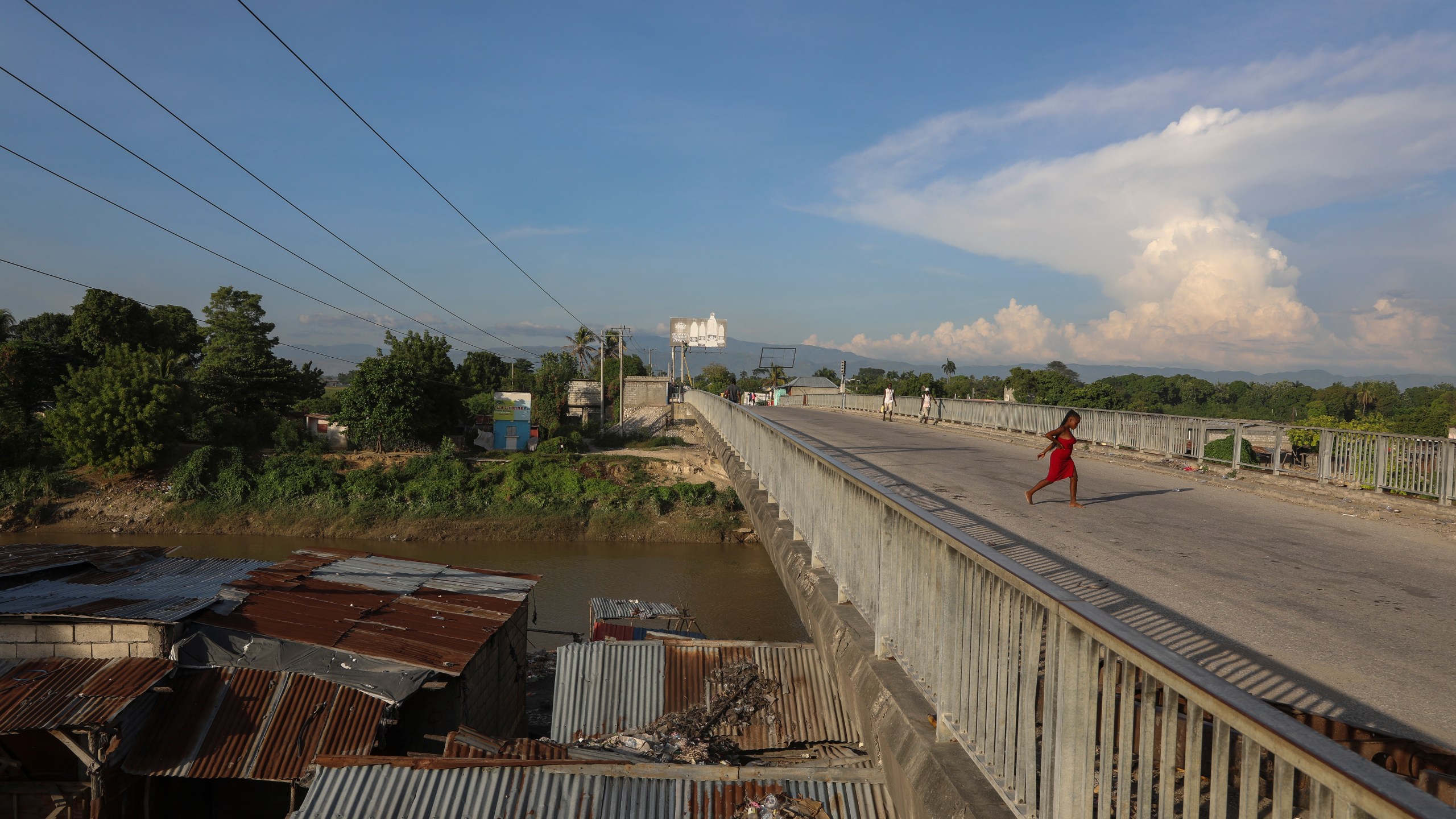 People walk across a bridge in Pont-Sonde, Haiti, Tuesday, Oct. 8, 2024, days after a deadly gang attack in the town. (AP Photo/Odelyn Joseph)