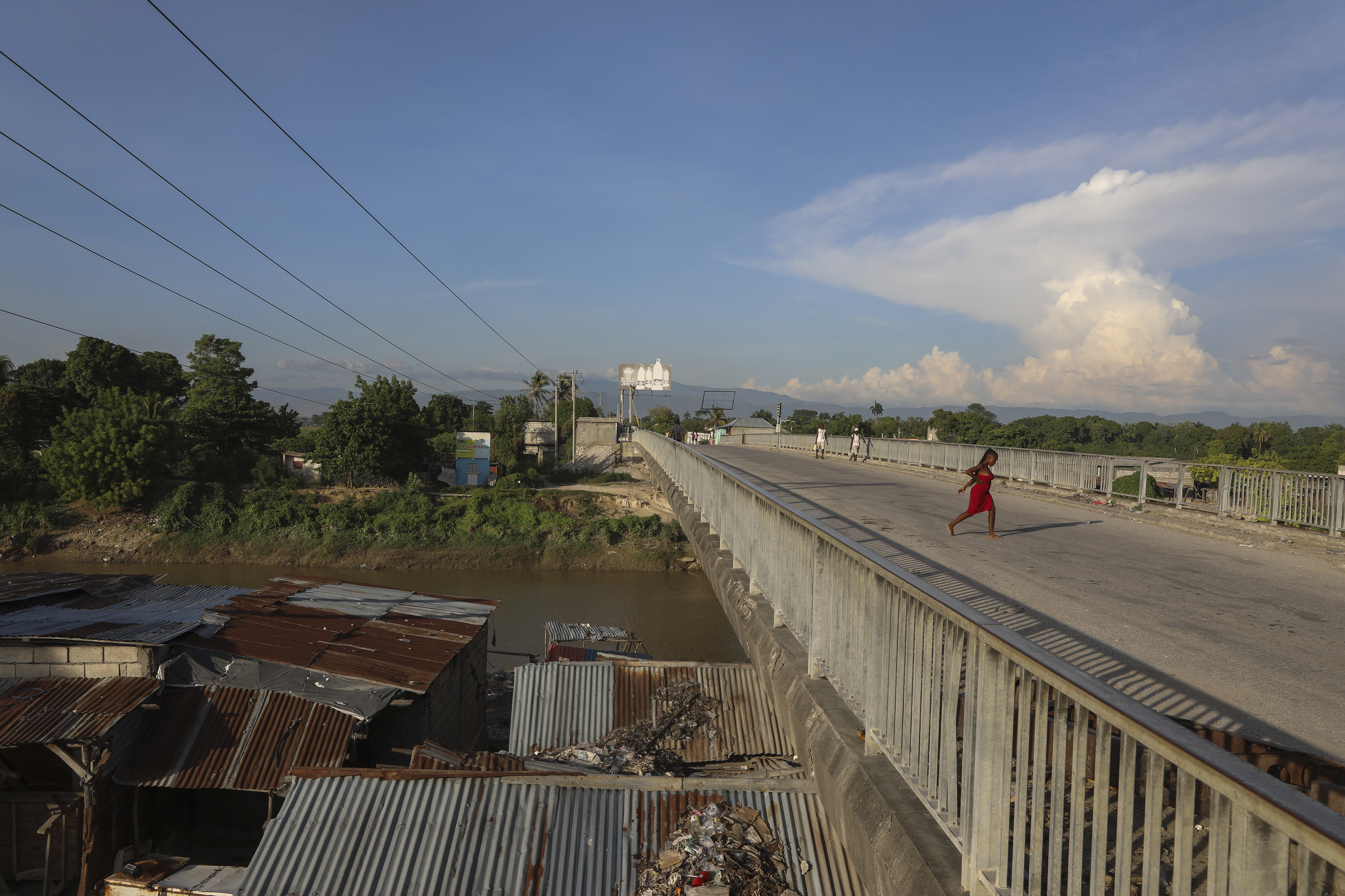 People walk across a bridge in Pont-Sonde, Haiti, Tuesday, Oct. 8, 2024, days after a deadly gang attack in the town. (AP Photo/Odelyn Joseph)