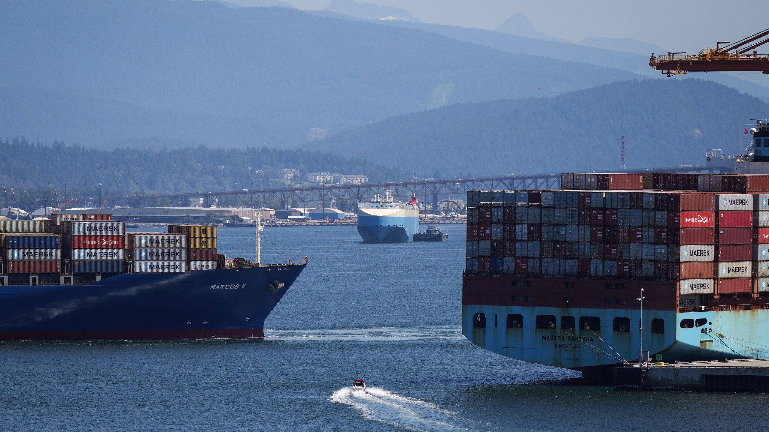 FILE - A boater passes between cargo ships on the harbor, in Vancouver, British Columbia, July 16, 2024. (Darryl Dyck/The Canadian Press via AP, File)