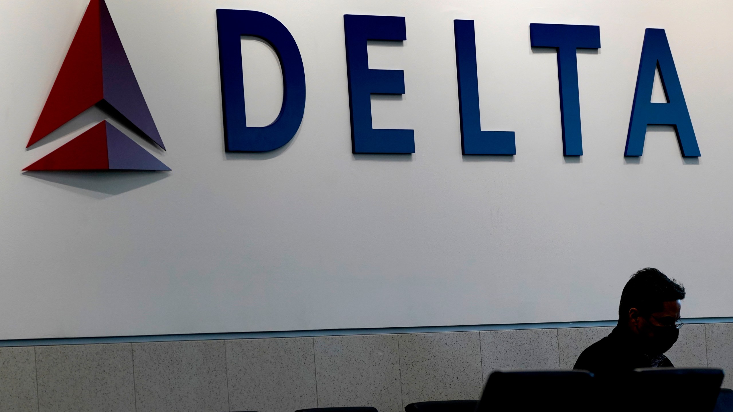 FILE - A man waits for a Delta Airlines flight at Hartsfield-Jackson International Airport in Atlanta, Jan. 7, 2022. (AP Photo/Charlie Riedel, File)