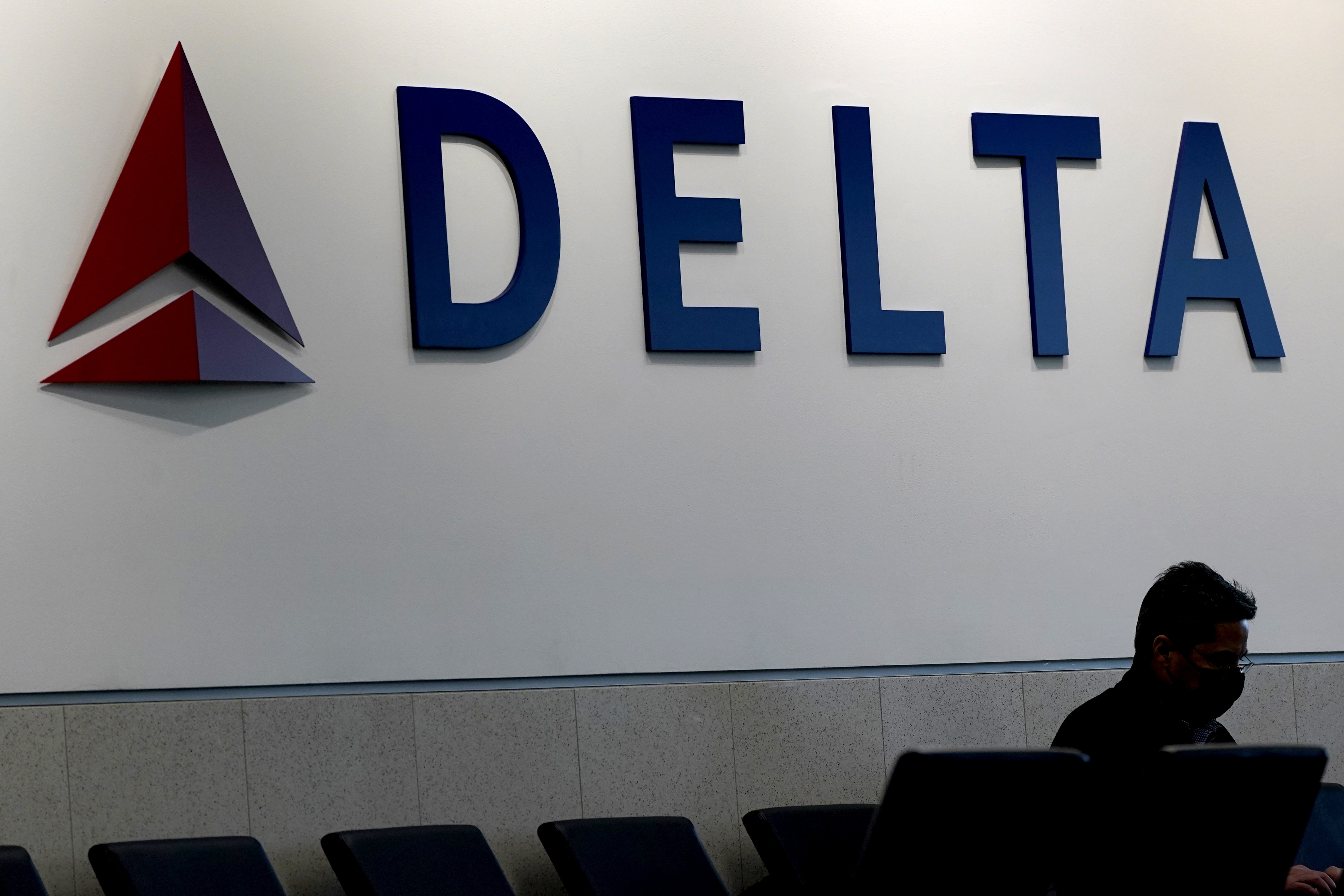 FILE - A man waits for a Delta Airlines flight at Hartsfield-Jackson International Airport in Atlanta, Jan. 7, 2022. (AP Photo/Charlie Riedel, File)