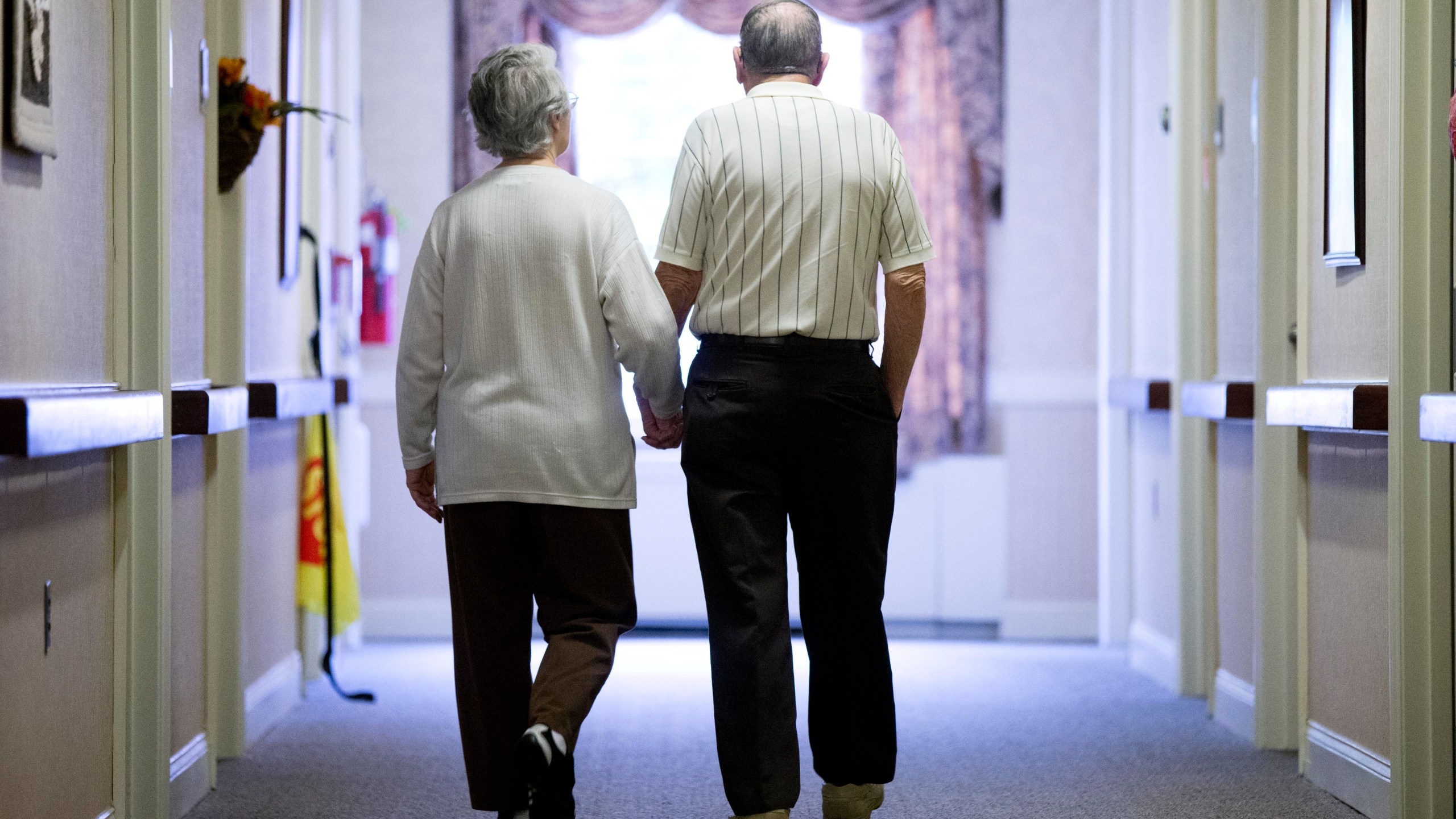 FILE - An elderly couple walks down a hall on Nov. 6, 2015 in Easton, Pa. (AP Photo/Matt Rourke, File)