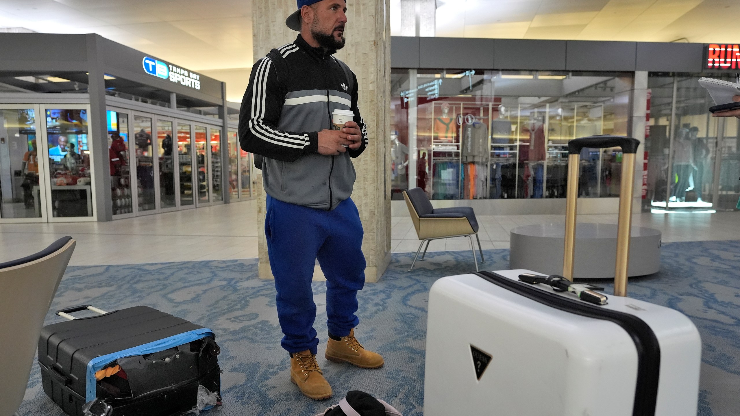 John Fedor, of New Jersey, waits for transportation help to get to a shelter after his flight was canceled Tuesday, Oct. 8, 2024, at the Tampa International Airport in Tampa, Fla., due to the possible arrival of Hurricane Milton. (AP Photo/Chris O'Meara)