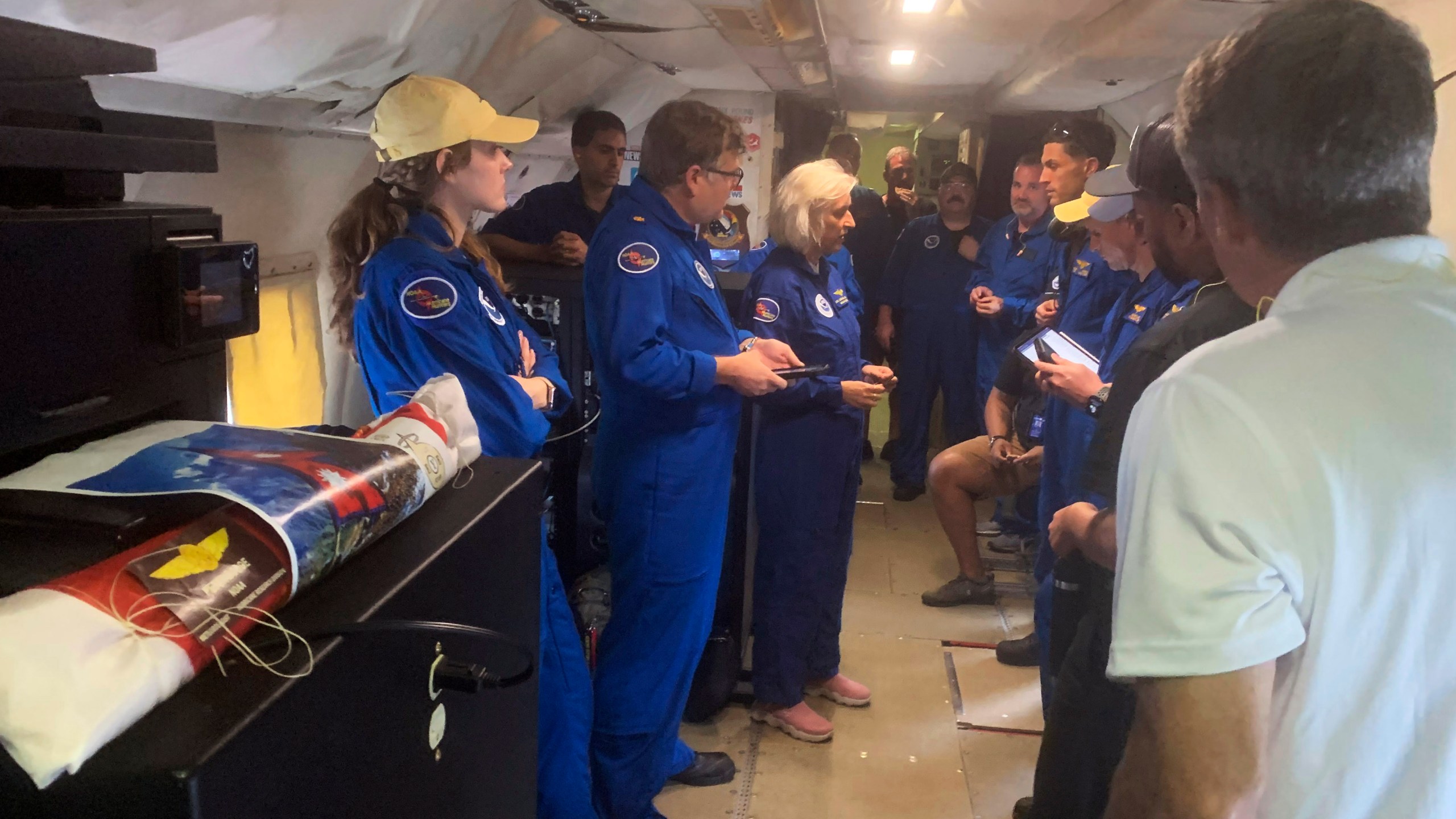 In this image released by the National Oceanic and Atmospheric Administration, a NOAA crew on a reconnaissance flight, Tuesday, Oct. 8, 2024, into the eye of Hurricane Milton in the Gulf of Mexico, gather before dropping a package containing the ashes of Peter Dodge, an award-winning scientist who made almost 400 hundreds flight into the eyes of hurricanes, as a lasting tribute to the longtime radar specialist and researcher. (Sim Aberson/NOAA via AP)