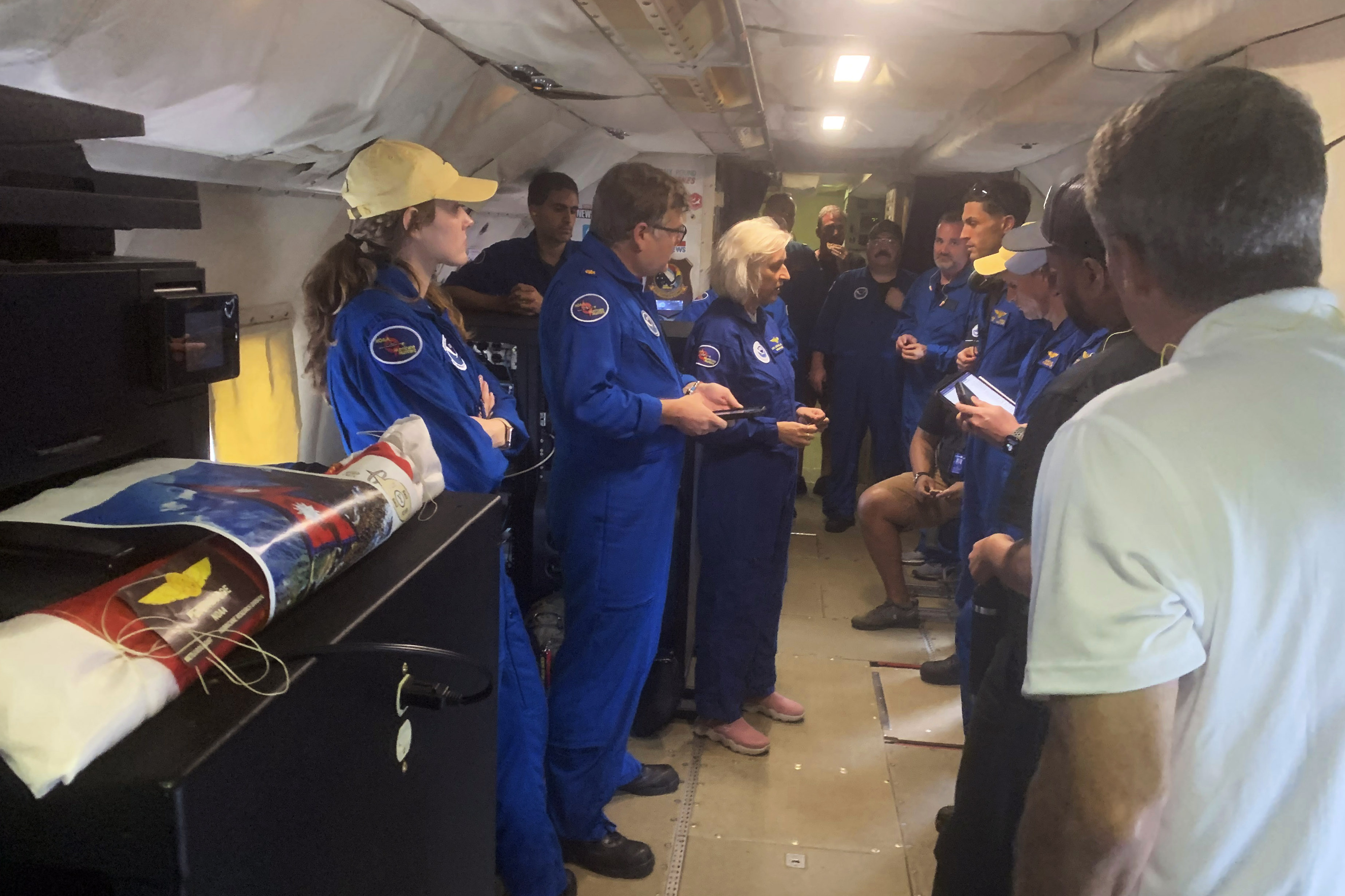 In this image released by the National Oceanic and Atmospheric Administration, a NOAA crew on a reconnaissance flight, Tuesday, Oct. 8, 2024, into the eye of Hurricane Milton in the Gulf of Mexico, gather before dropping a package containing the ashes of Peter Dodge, an award-winning scientist who made almost 400 hundreds flight into the eyes of hurricanes, as a lasting tribute to the longtime radar specialist and researcher. (Sim Aberson/NOAA via AP)