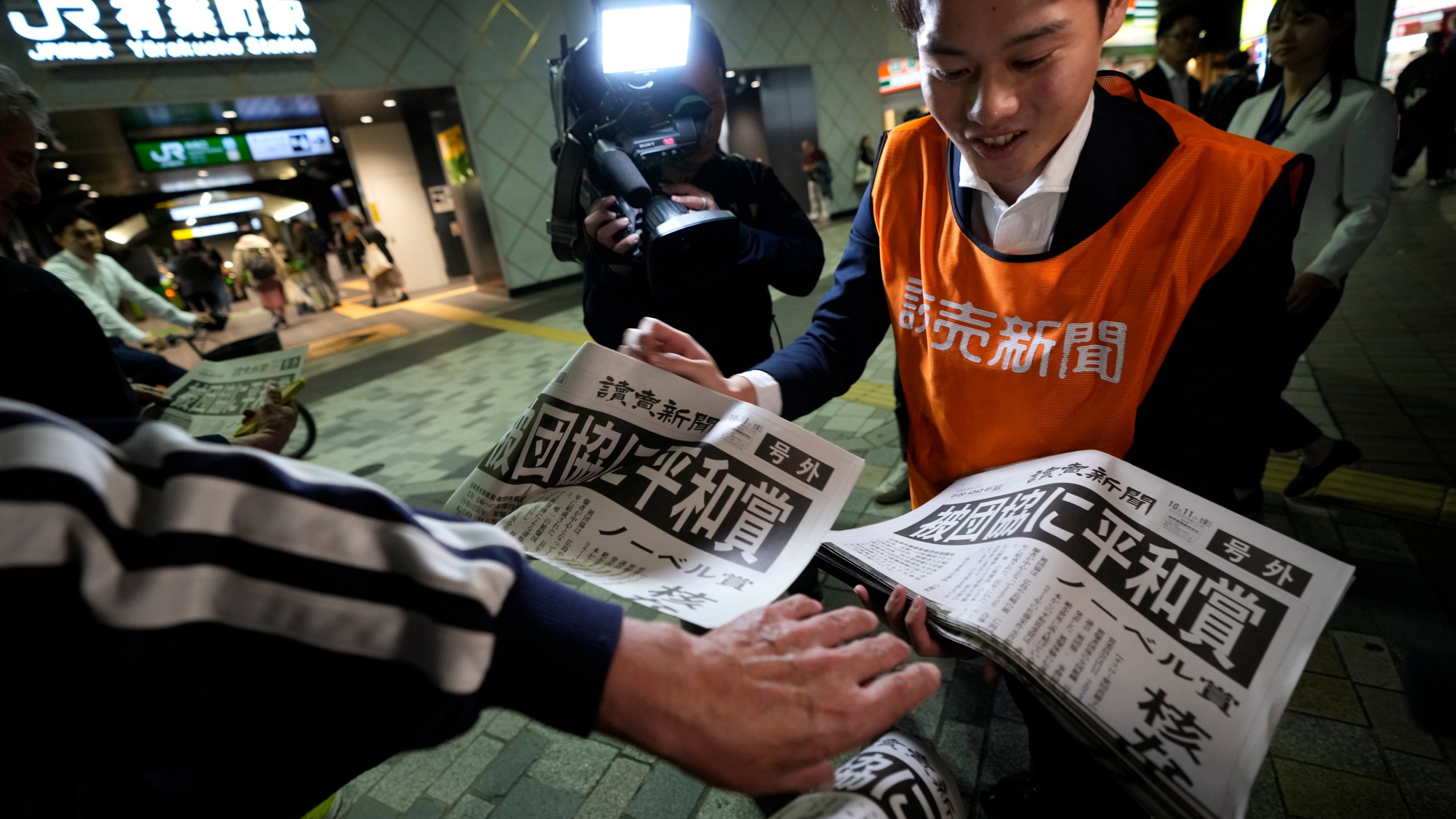 A worker of the Yomiuri Shimbun newspaper hands out copies of an extra version to passersby in Tokyo, Friday, Oct. 11, 2024, after Nihon Hidankyo, or the Japan Confederation of A- and H-Bomb Sufferers Organizations, won the Nobel Peace Prize. (AP Photo/Shuji Kajiyama)