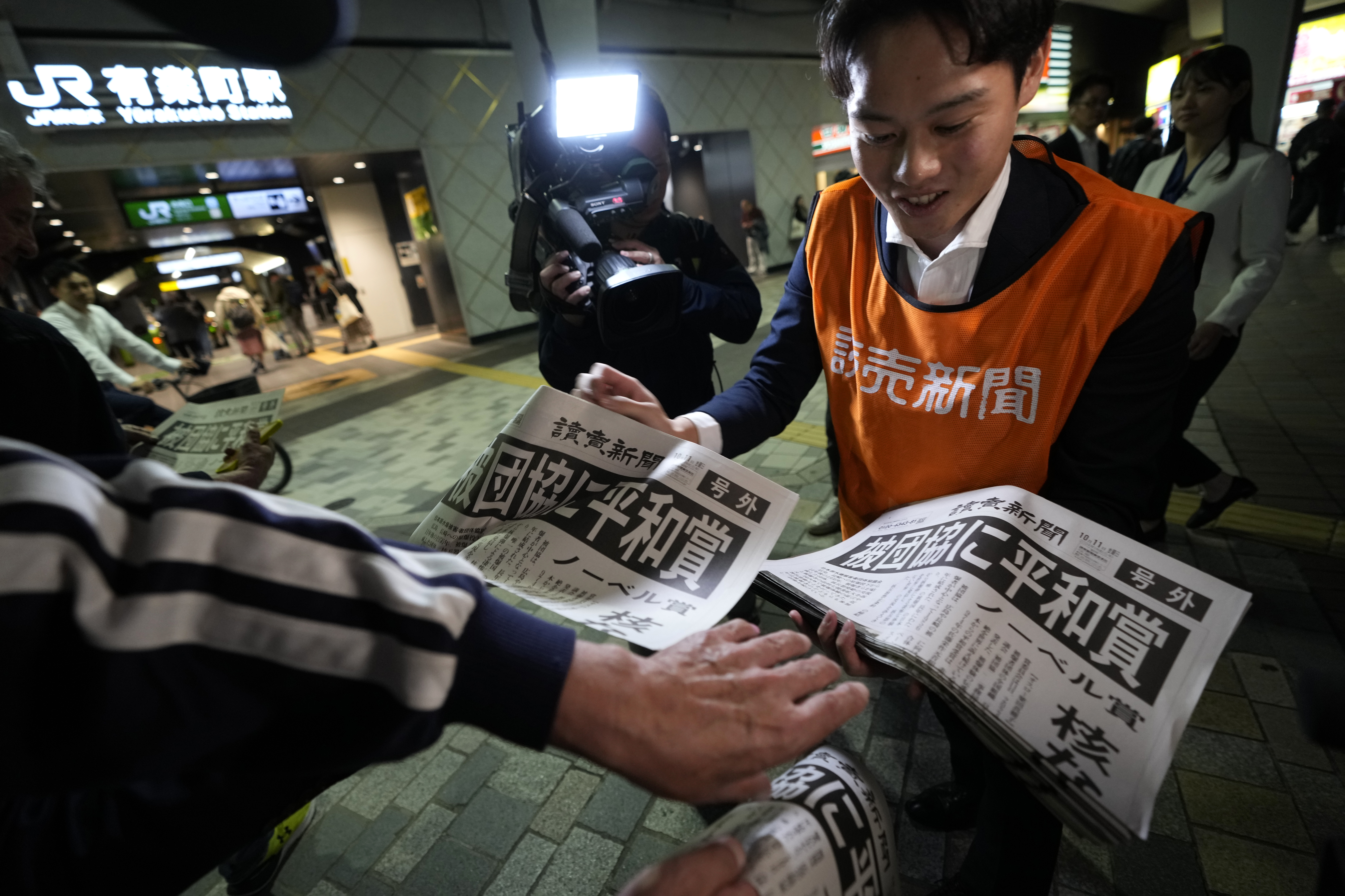 A worker of the Yomiuri Shimbun newspaper hands out copies of an extra version to passersby in Tokyo, Friday, Oct. 11, 2024, after Nihon Hidankyo, or the Japan Confederation of A- and H-Bomb Sufferers Organizations, won the Nobel Peace Prize. (AP Photo/Shuji Kajiyama)