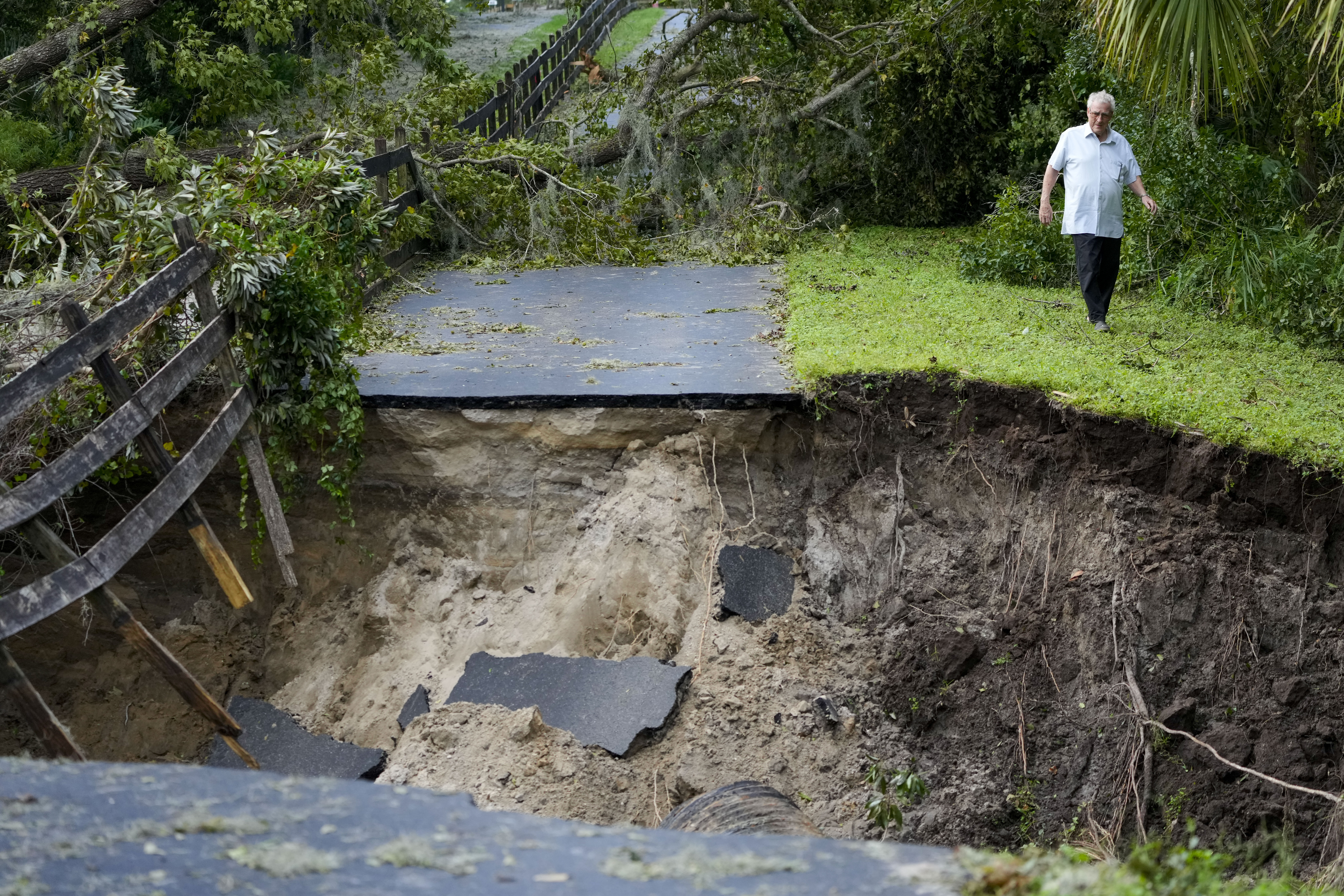 Del Ockey, a seasonal Florida resident from Canada, walks near the damaged bridge from Hurricane Milton, that leads onto his property, Friday, Oct. 11, 2024, in Riverview, Fla. (AP Photo/Julio Cortez)