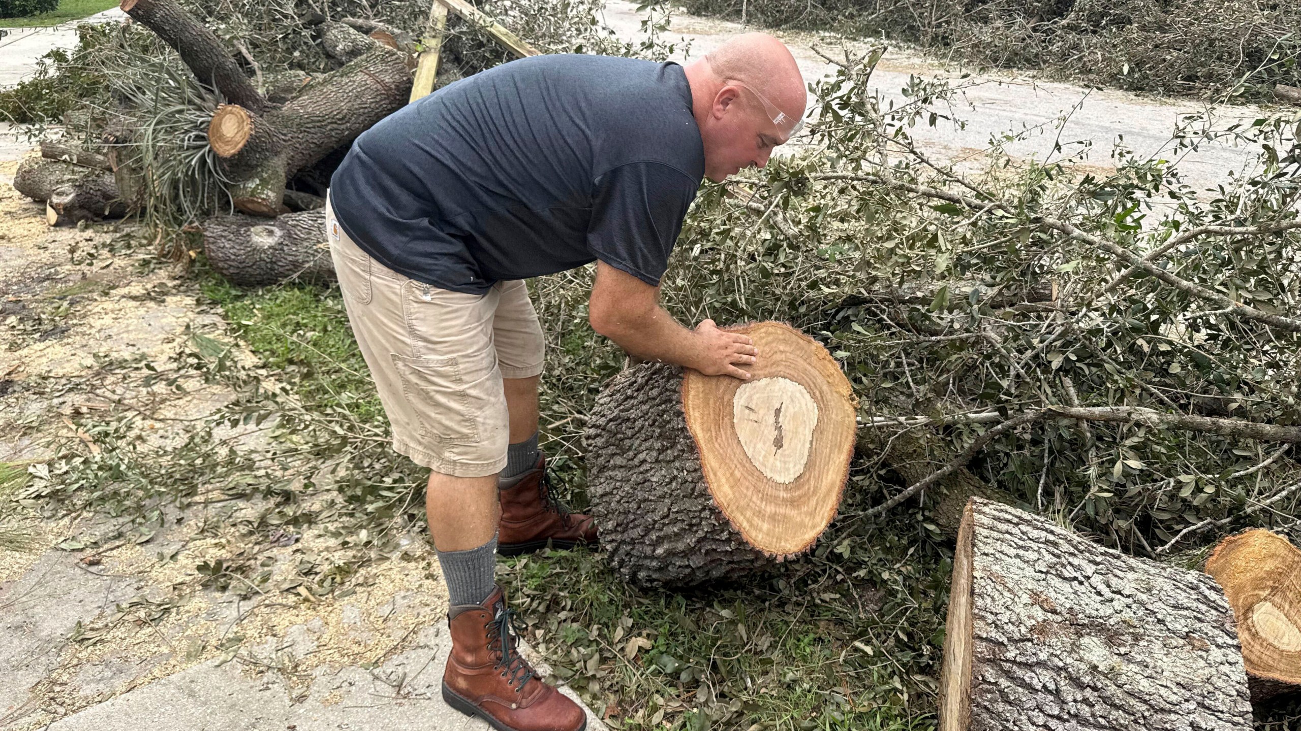 Tony Brazzale removes part of a tree felled by a tornado from in front of his house in Wellington, Fla., Friday, Oct. 11, 2024. (AP Photo/Stephany Matat)