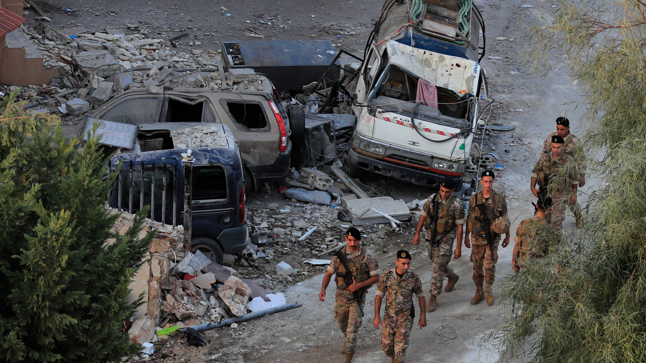 Lebanese army soldiers walk by destroyed cars at the site where an Israeli airstrike hit a building, in Barja village, south of Beirut, Lebanon, Saturday, Oct. 12, 2024. (AP Photo/Mohammed Zaatari)