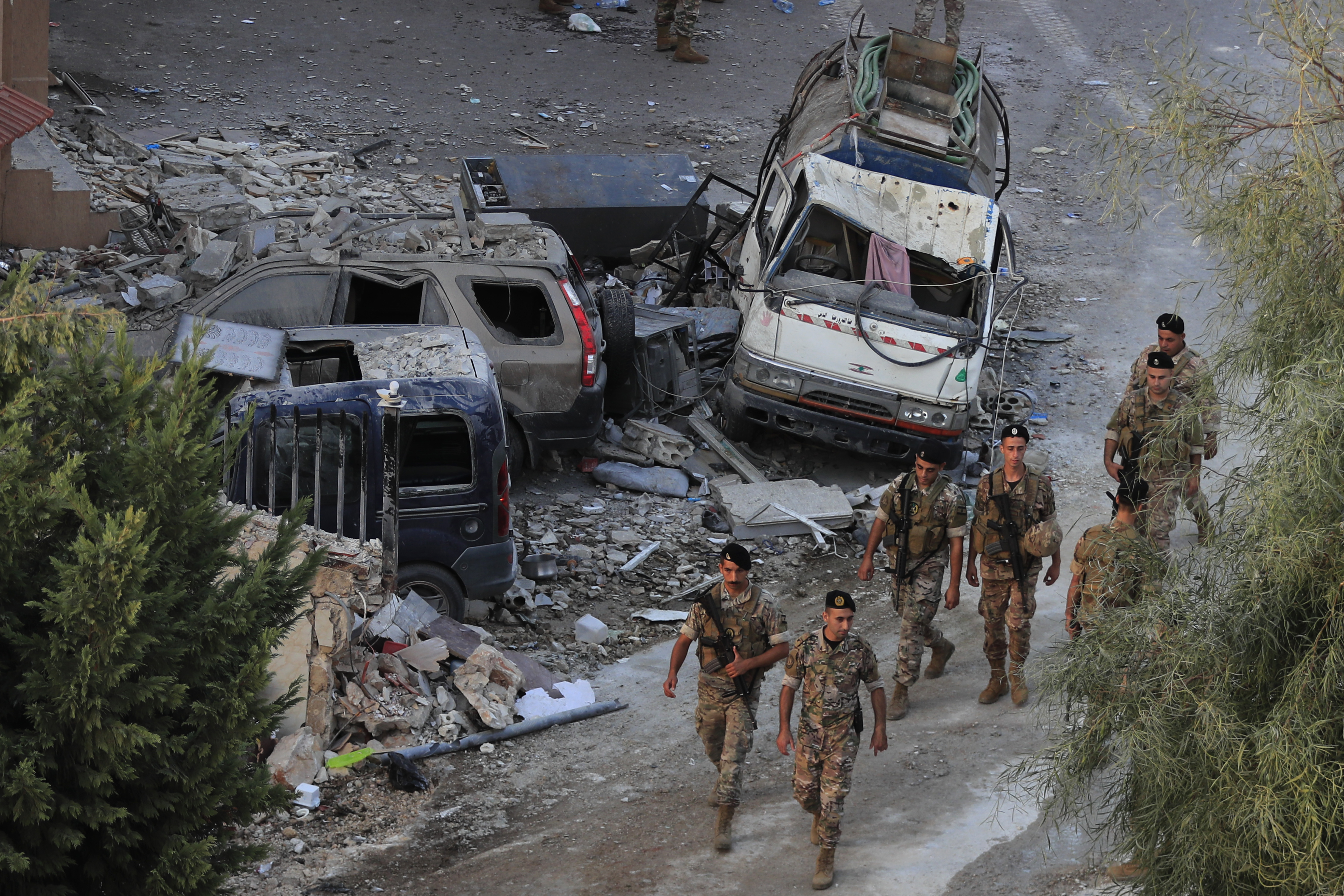 Lebanese army soldiers walk by destroyed cars at the site where an Israeli airstrike hit a building, in Barja village, south of Beirut, Lebanon, Saturday, Oct. 12, 2024. (AP Photo/Mohammed Zaatari)