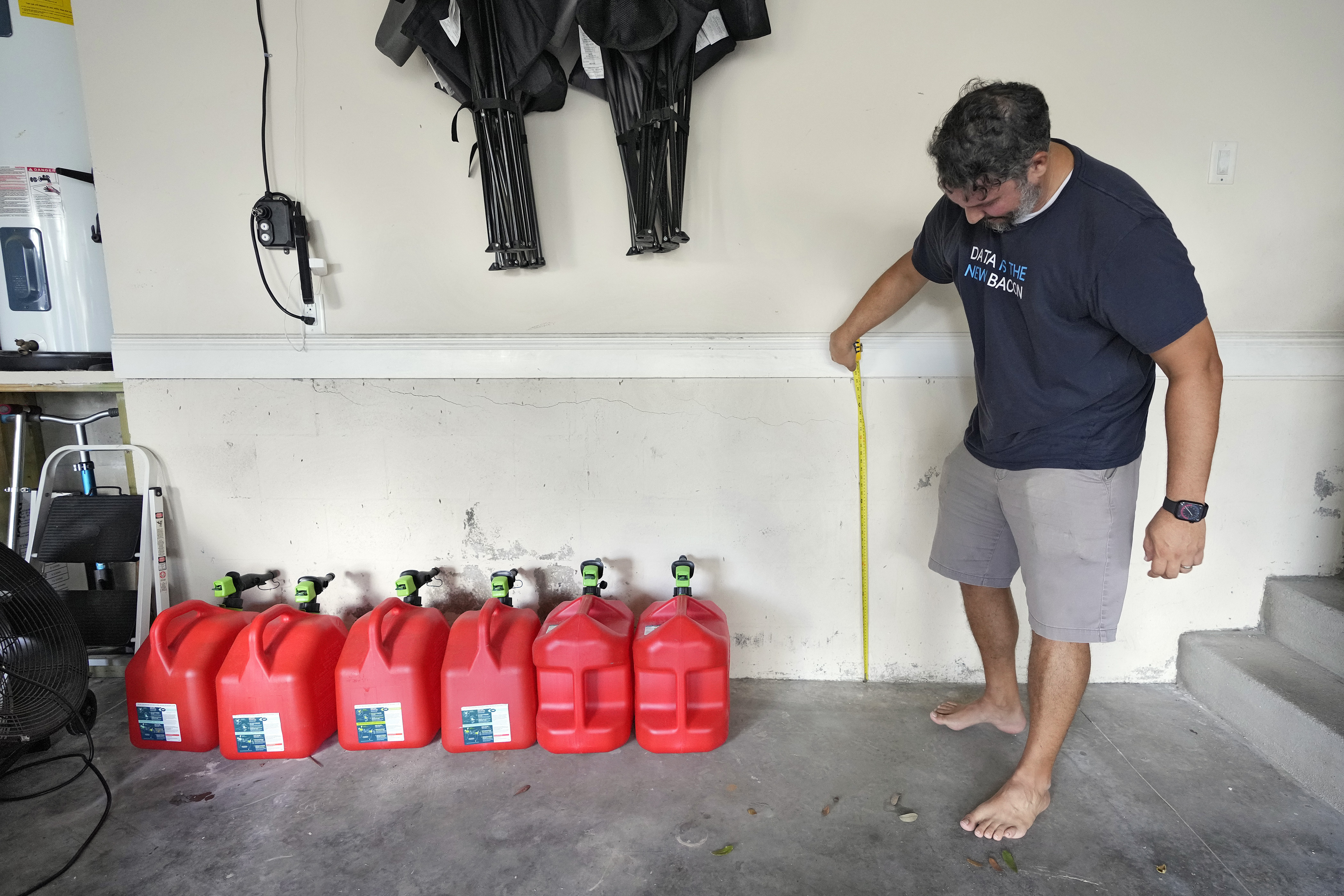 Chris Sundar measures the depth of floodwaters from Hurricane Milton in his garage Sunday, Oct. 13, 2024, in Tampa, Fla. (AP Photo/Chris O'Meara)