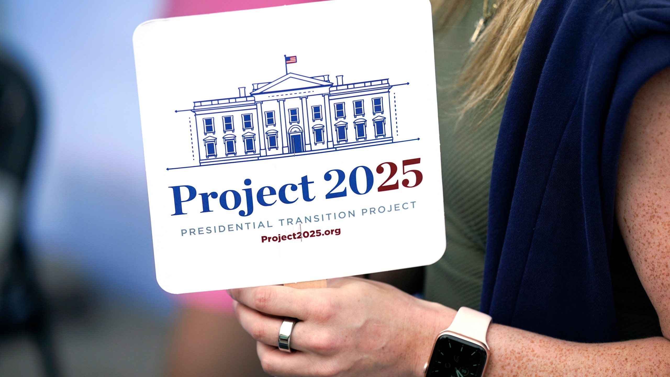 FILE - Kristen Eichamer holds a Project 2025 fan in the group's tent at the Iowa State Fair, Aug. 14, 2023, in Des Moines, Iowa. (AP Photo/Charlie Neibergall, File)