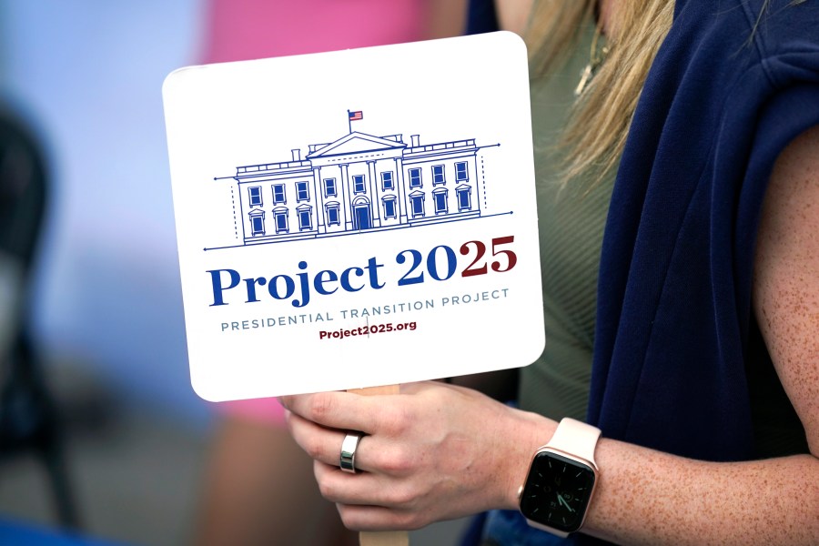 FILE - Kristen Eichamer holds a Project 2025 fan in the group's tent at the Iowa State Fair, Aug. 14, 2023, in Des Moines, Iowa. (AP Photo/Charlie Neibergall, File)