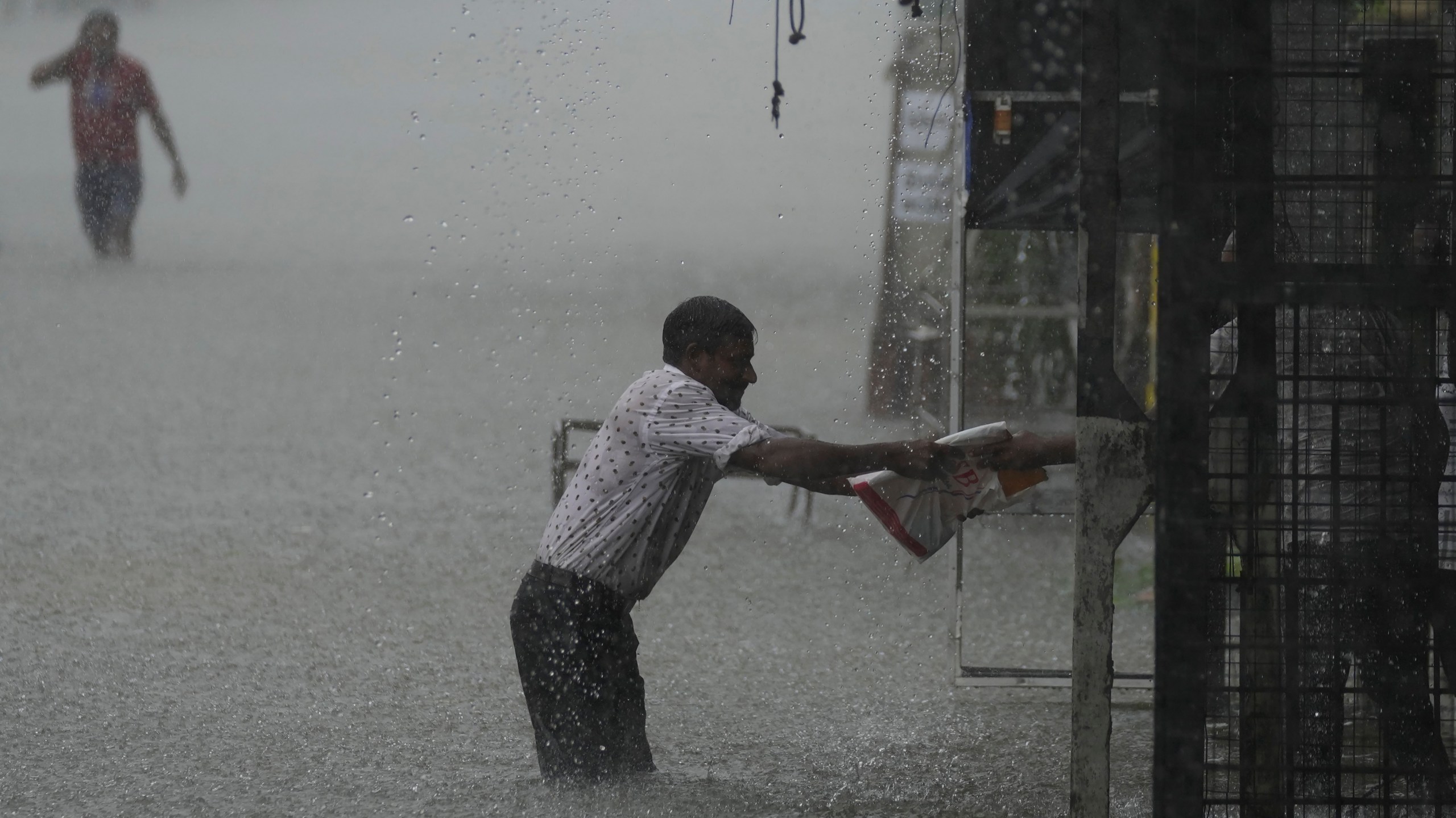 A man reaches for a safe place as it rains in a flooded street in Colombo, Sri Lanka, Sunday, Oct. 13, 2024. (AP Photo/Eranga Jayawardena)