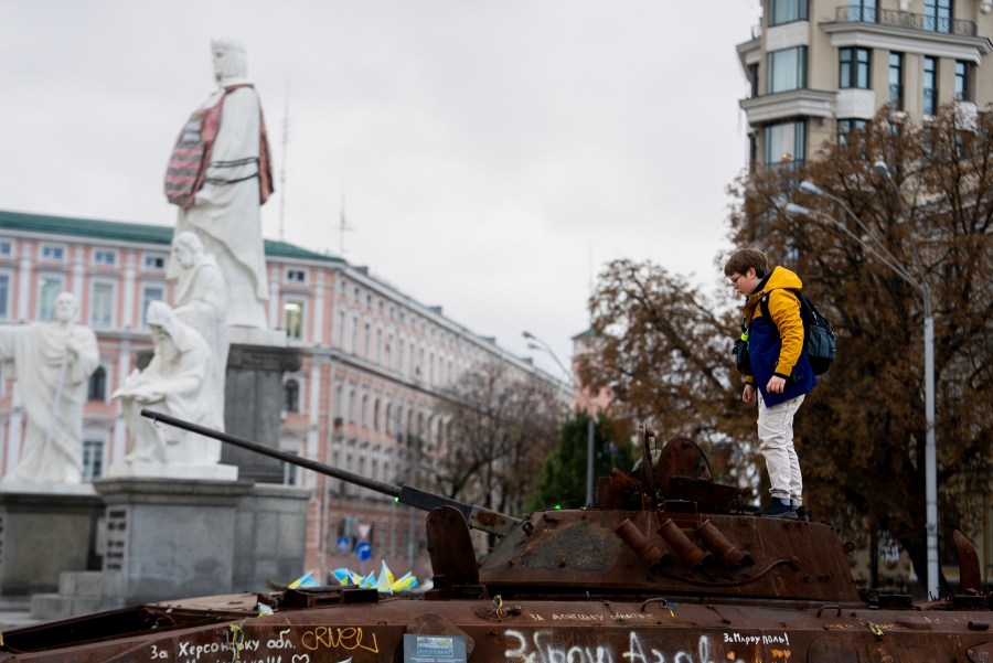 A boy stands on Russian burned APC in central Kyiv, Ukraine, Monday, Oct. 14, 2024. (AP Photo/Alex Babenko)