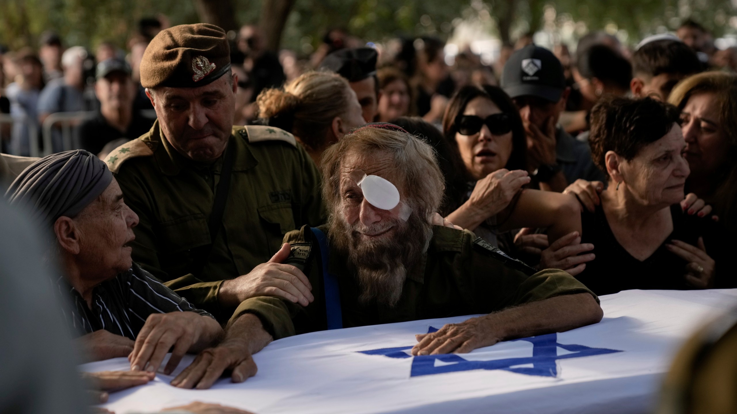 People mourn over the flagged-covered coffin of Israeli soldier Sgt. Amitai Alon, killed by a Hezbollah drone attack, during his funeral near Ramot Naftali, Israel, Monday, Oct. 14, 2024. (AP Photo/Leo Correa)