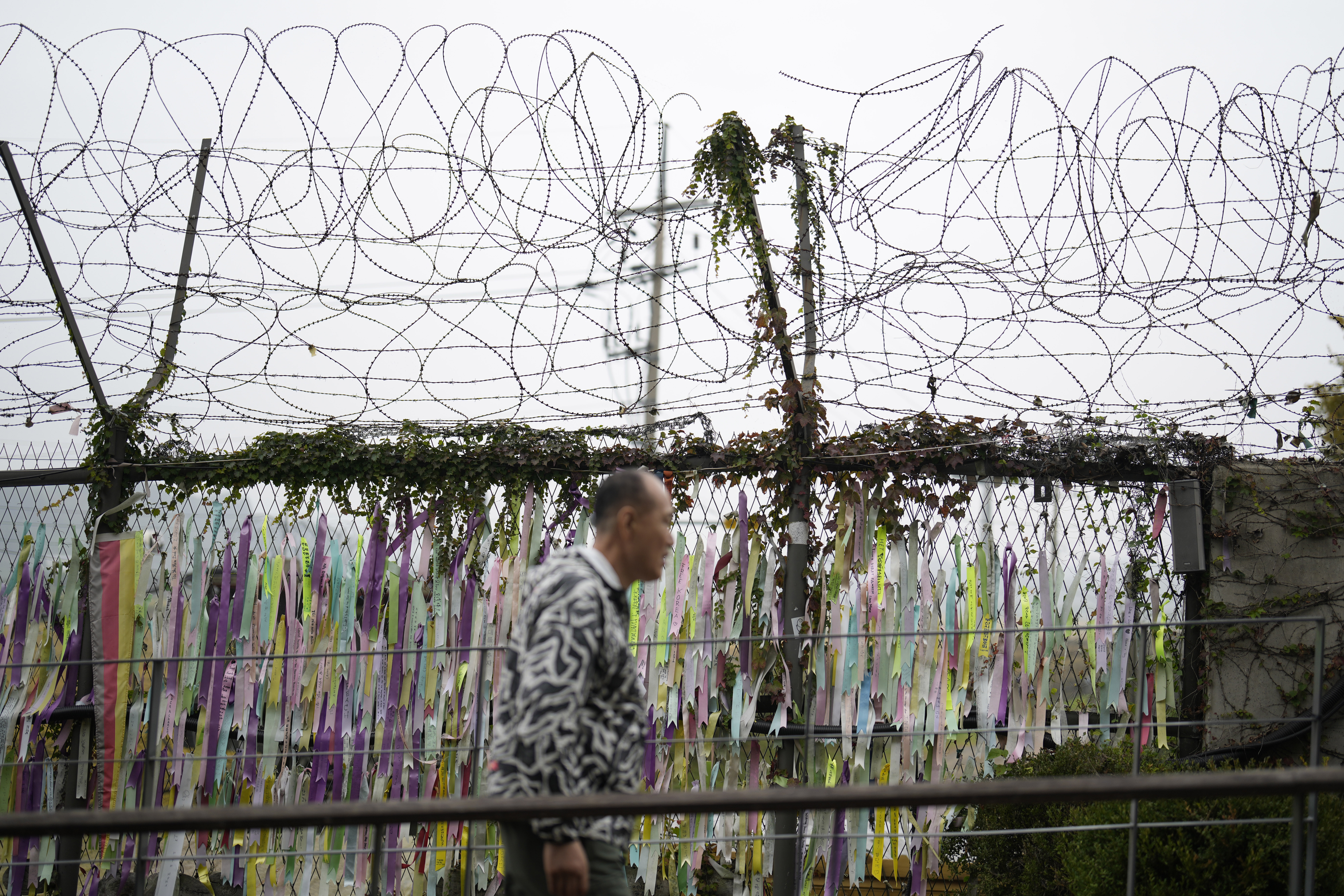 A visitor walks near a wire fence decorated with ribbons written with messages wishing for the reunification of the two Koreas at the Imjingak Pavilion in Paju, South Korea, Tuesday, Oct. 15, 2024. (AP Photo/Lee Jin-man)