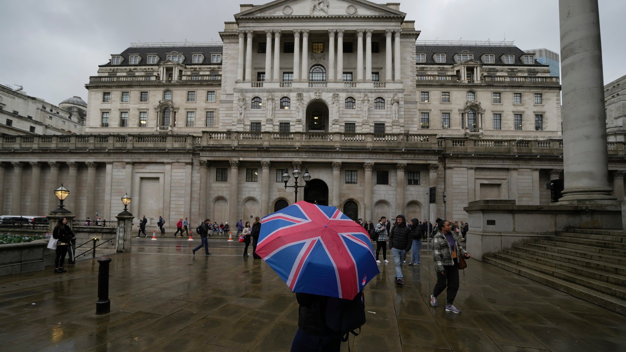 FILE -A woman with an umbrella stands in front of the Bank of England, at the financial district in London, , Nov. 3, 2022. (AP Photo/Kin Cheung, File)