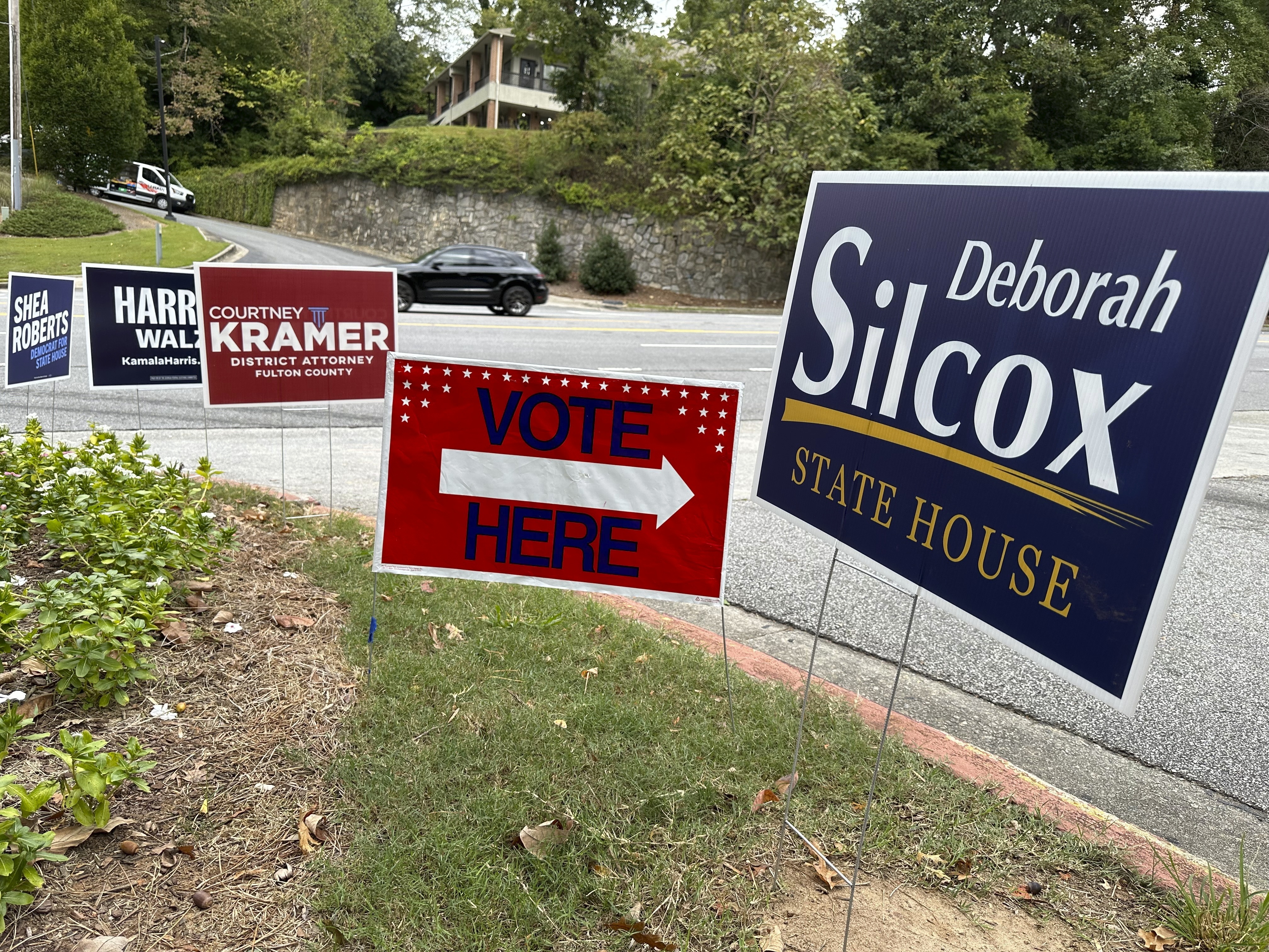 Signs entice voters in the Atlanta suburb of Sandy Springs, Ga., Tuesday, Oct. 15, 2024, the first day of early in-person voting in Georgia. (AP Photo/Jeff Amy)