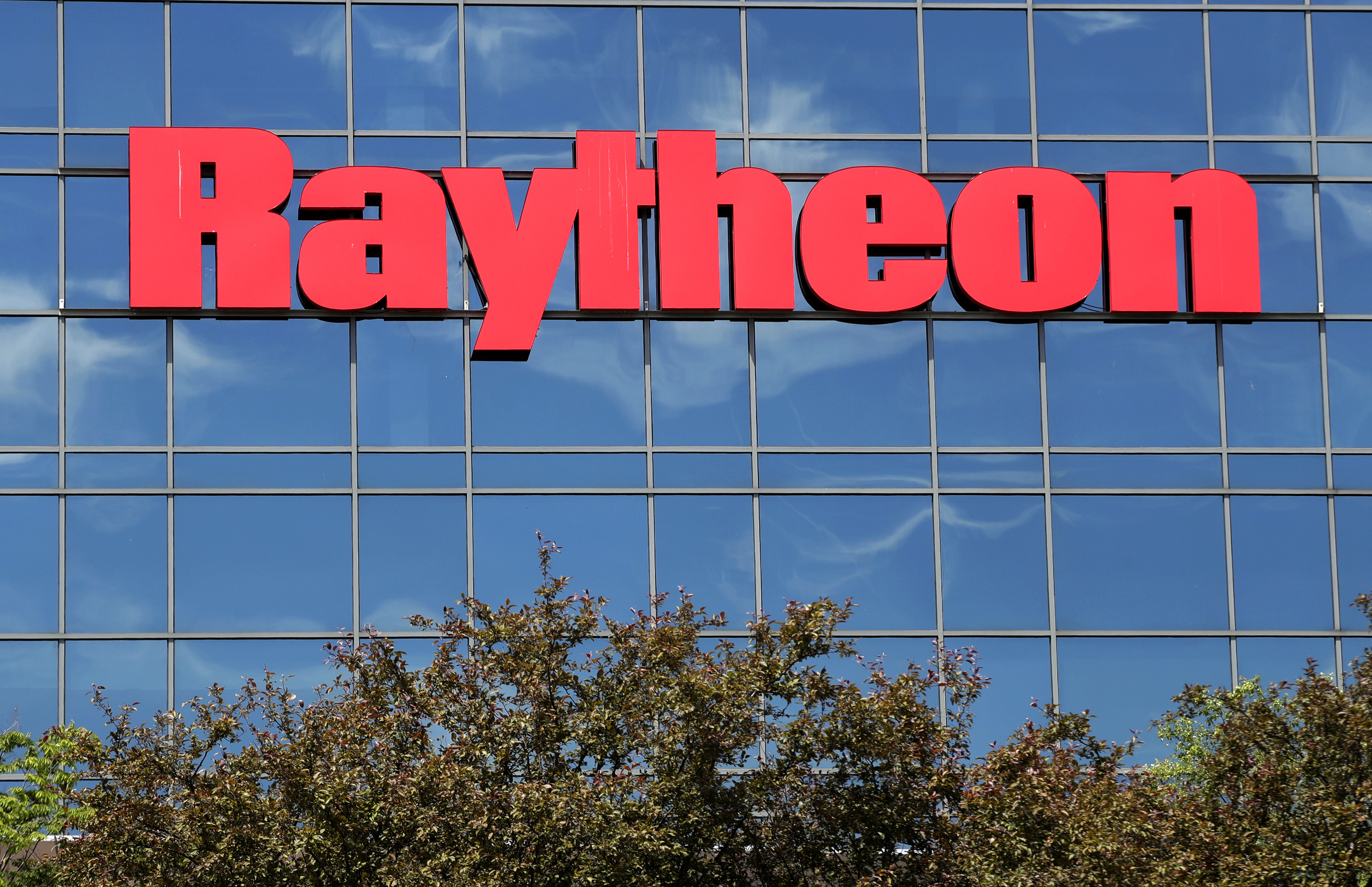 FILE - The sky is reflected on the facade of Raytheon's Integrated Defense Systems facility, Monday, June 10, 2019, in Woburn, Mass. (AP Photo/Elise Amendola, File)