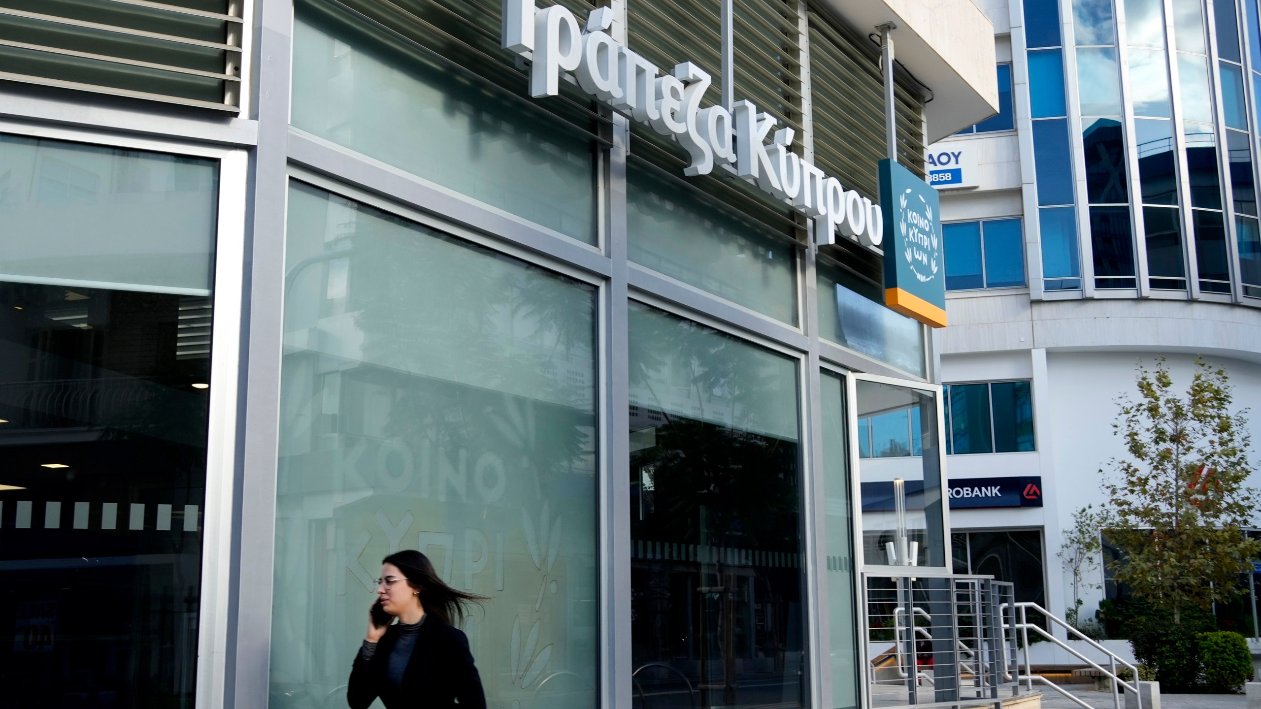 FILE - A woman walks outside of a branch of "Bank of Cyprus" in Nicosia, Cyprus, Wednesday, Jan. 24, 2024. (AP Photo/Petros Karadjias, File)