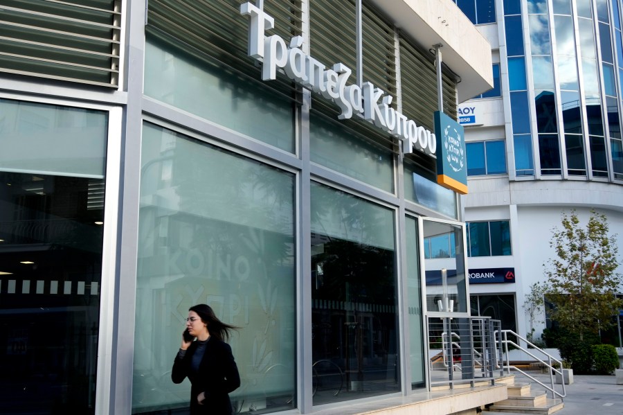 FILE - A woman walks outside of a branch of "Bank of Cyprus" in Nicosia, Cyprus, Wednesday, Jan. 24, 2024. (AP Photo/Petros Karadjias, File)