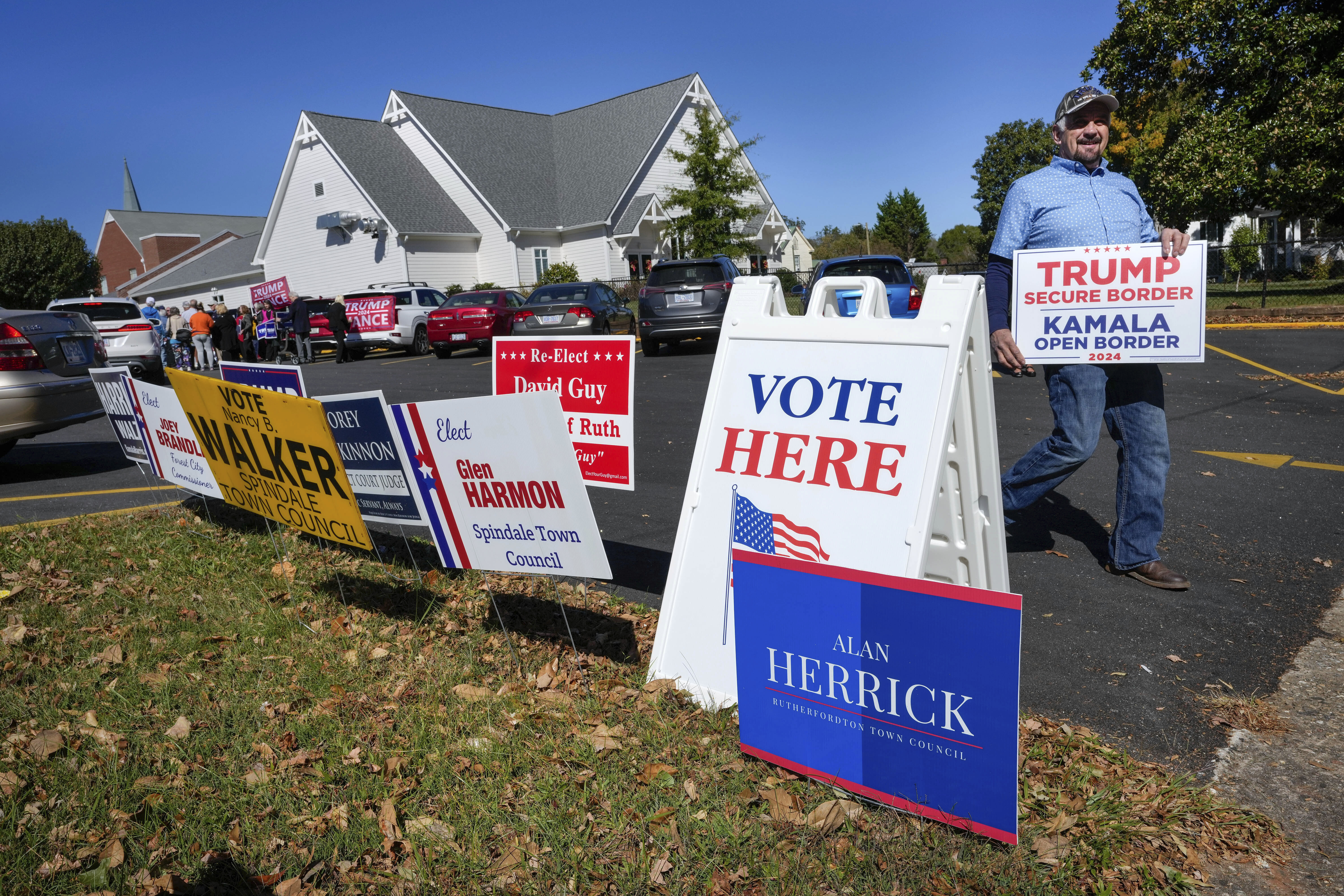 A supporter for former President Trump walks past political signs outside the Rutherford County Annex Building, an early voting site, Thursday, Oct. 17, 2024 in Rutherfordton, N.C. (AP Photo/Kathy Kmonicek)