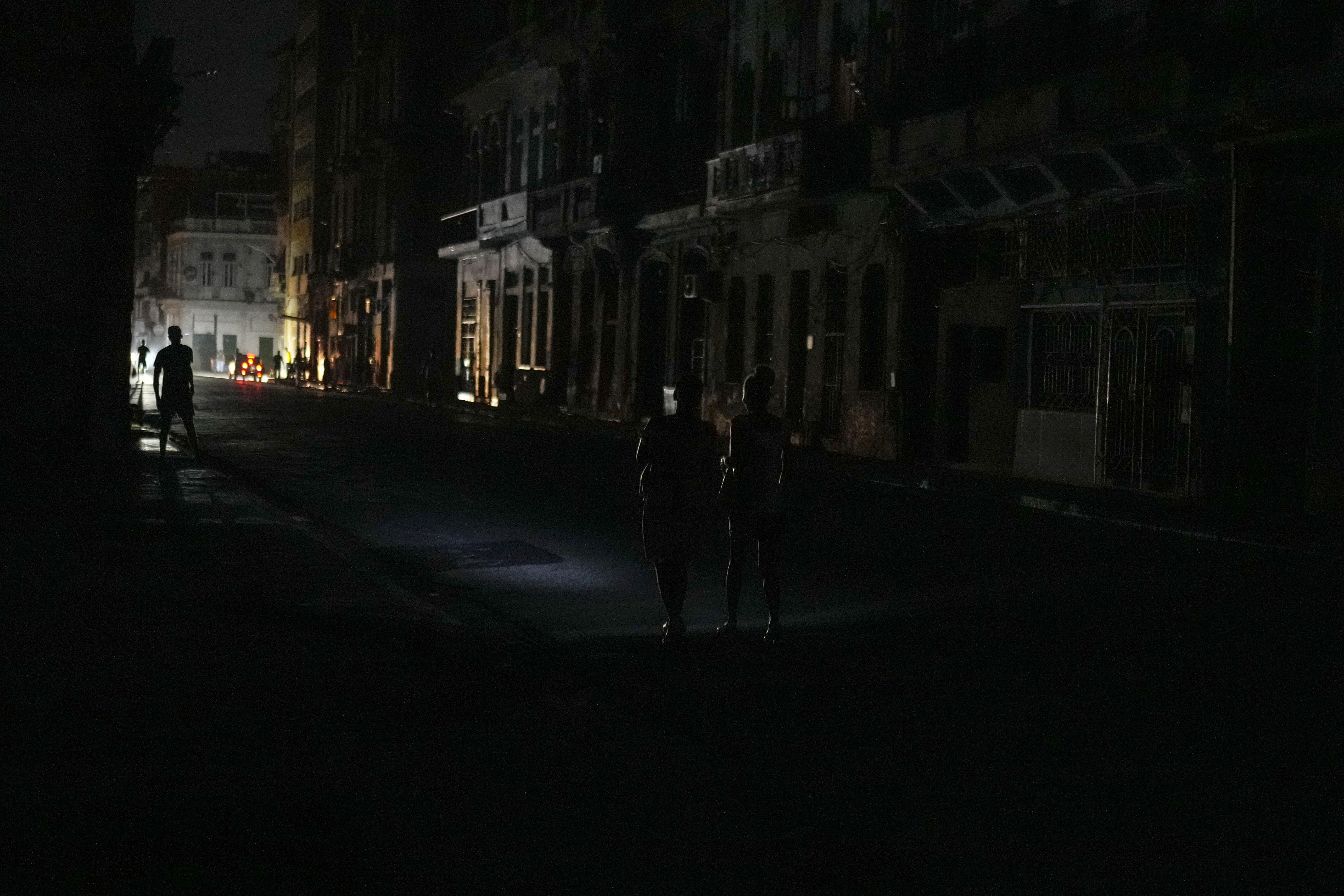 Residents walk along a street during a massive blackout after a major power plant failed in Havana, Cuba, Friday, Oct. 18, 2024. (AP Photo/Ramon Espinosa)