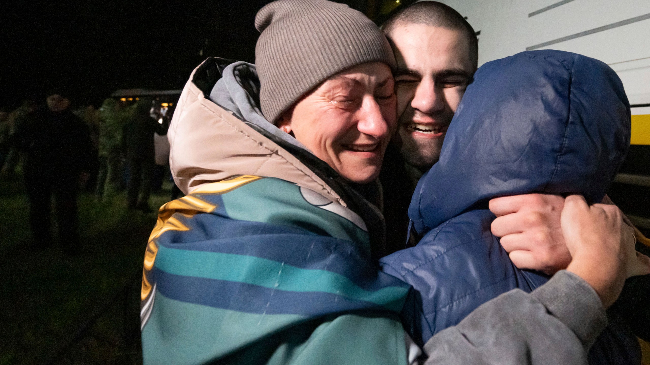 In this photo provided by the Press Service of the President of Ukraine on Oct. 19, 2024, a Ukrainian serviceman hugs his family after returning from captivity during a POWs exchange in an undisclosed location, Ukraine. (Press Service of the President of Ukraine via AP)