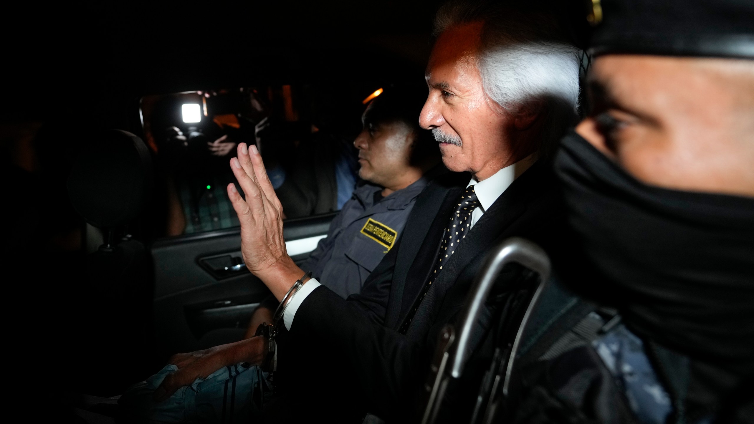 Guatemalan journalist Jose Ruben Zamora, founder of El Periodico newspaper, jailed for more than two years on money laundering charges, waves from inside a police car after a judge granted him house arrest, in Guatemala City, Friday, Oct. 18, 2024. (AP Photo/Moises Castillo)