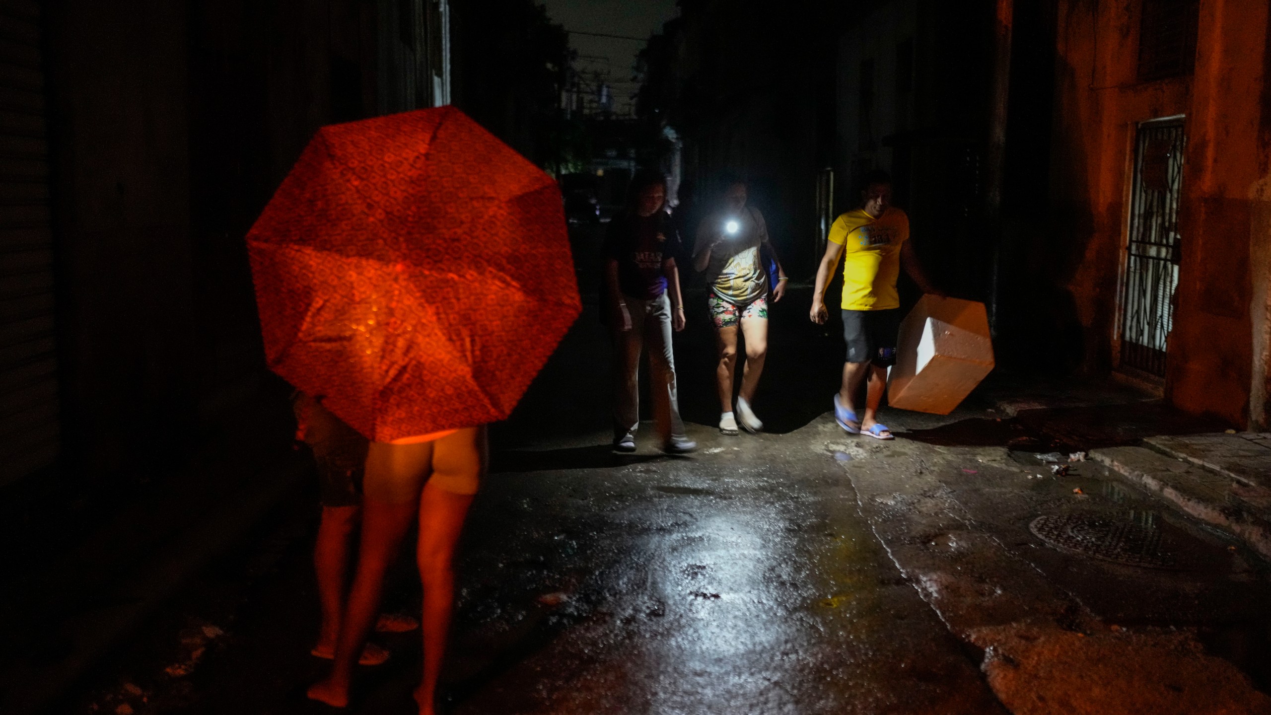 Residents walk down a street using a phone flashlight during a power outage following the failure of a major power plant in Havana, Cuba, Saturday, Oct. 19, 2024. (AP Photo/Ramon Espinosa)