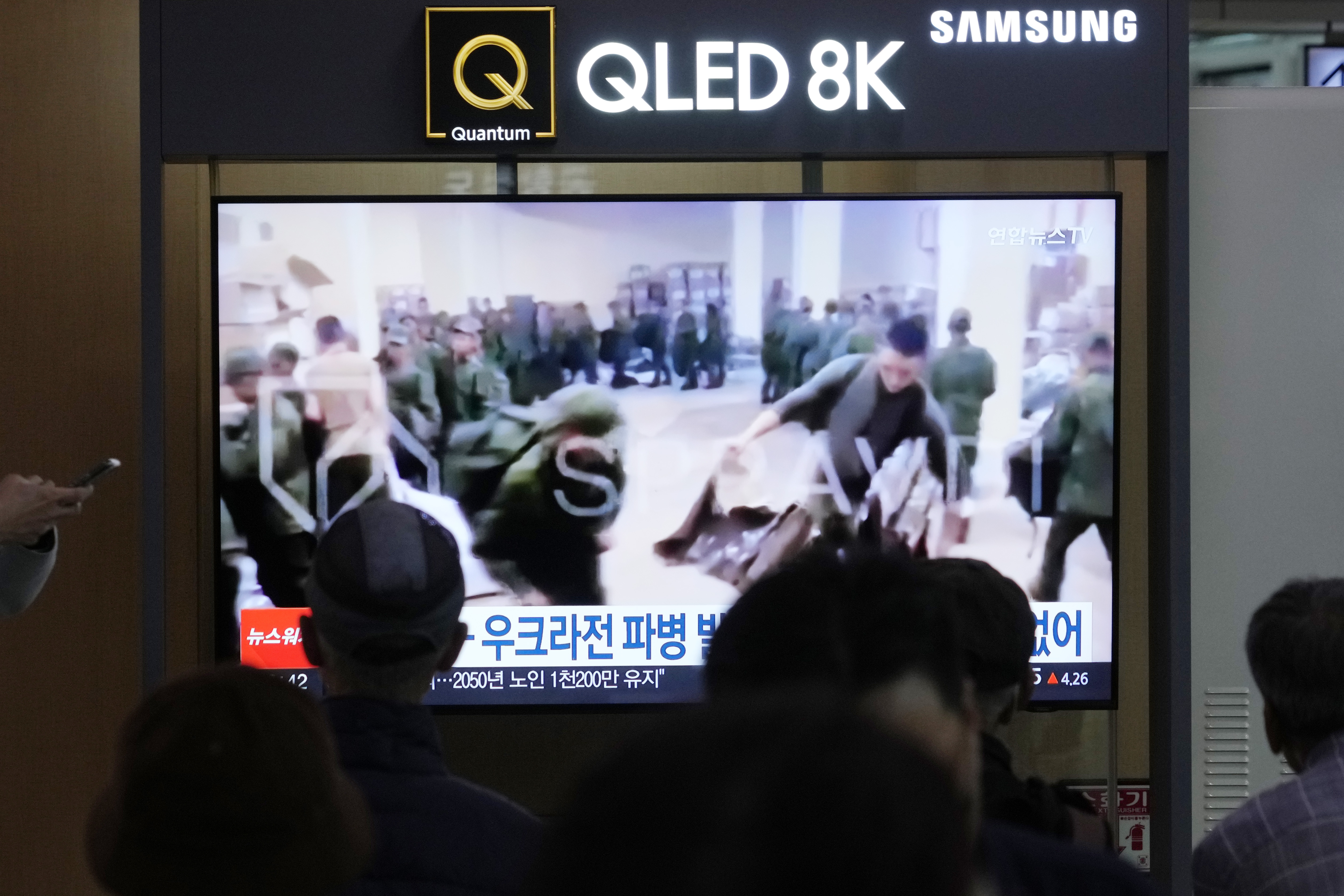 A TV screen shows an image of soldiers believed to be from North Korea stand in line to receive supplies from Russia during a news program at Seoul Railway Station in Seoul, South Korea, Monday, Oct. 21, 2024. (AP Photo/Ahn Young-joon)