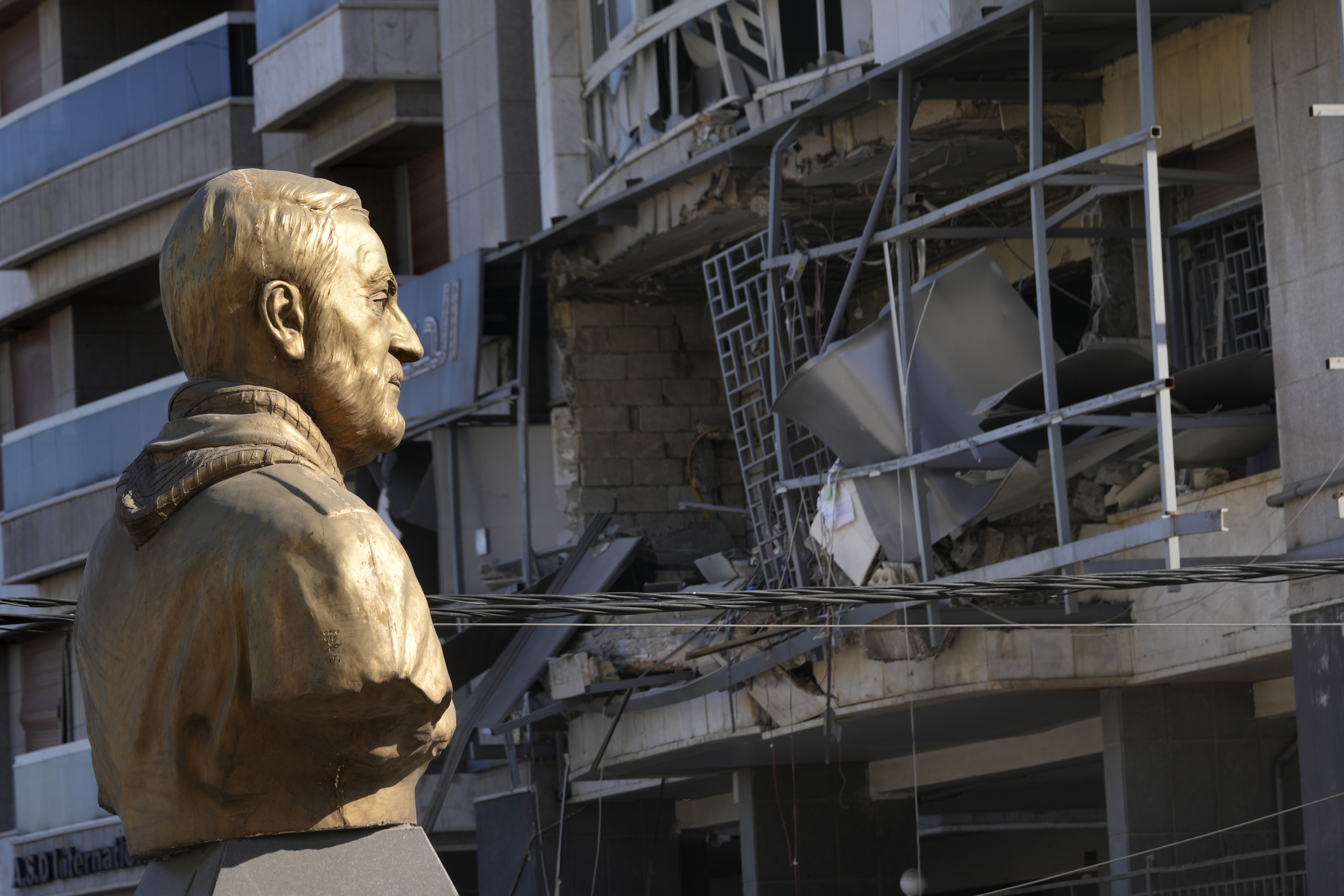 A bust of the late Iranian General Qassem Soleimani stands in front of a destroyed branch of the Hezbollah-run Qard al-Hassan, which was hit by an Israeli airstrike in Dahiyeh, Beirut, Lebanon, Monday, Oct. 21, 2024. (AP Photo/Hussein Malla)