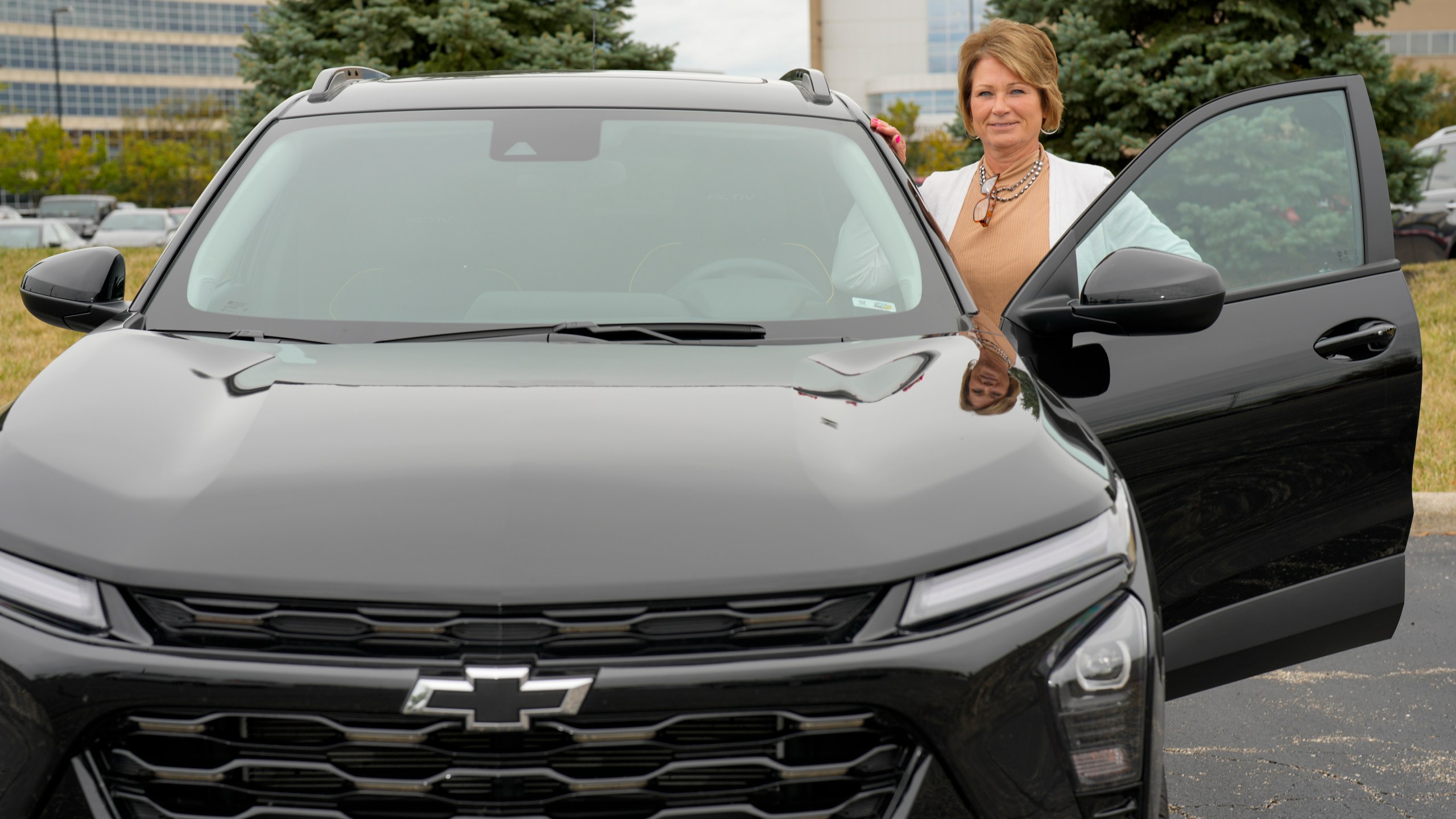 Michelle Chumley poses with her new Chevrolet Trax compact SUV, Thursday, Sept. 26, 2024, in West Chester, Ohio. (AP Photo/Jeff Dean)