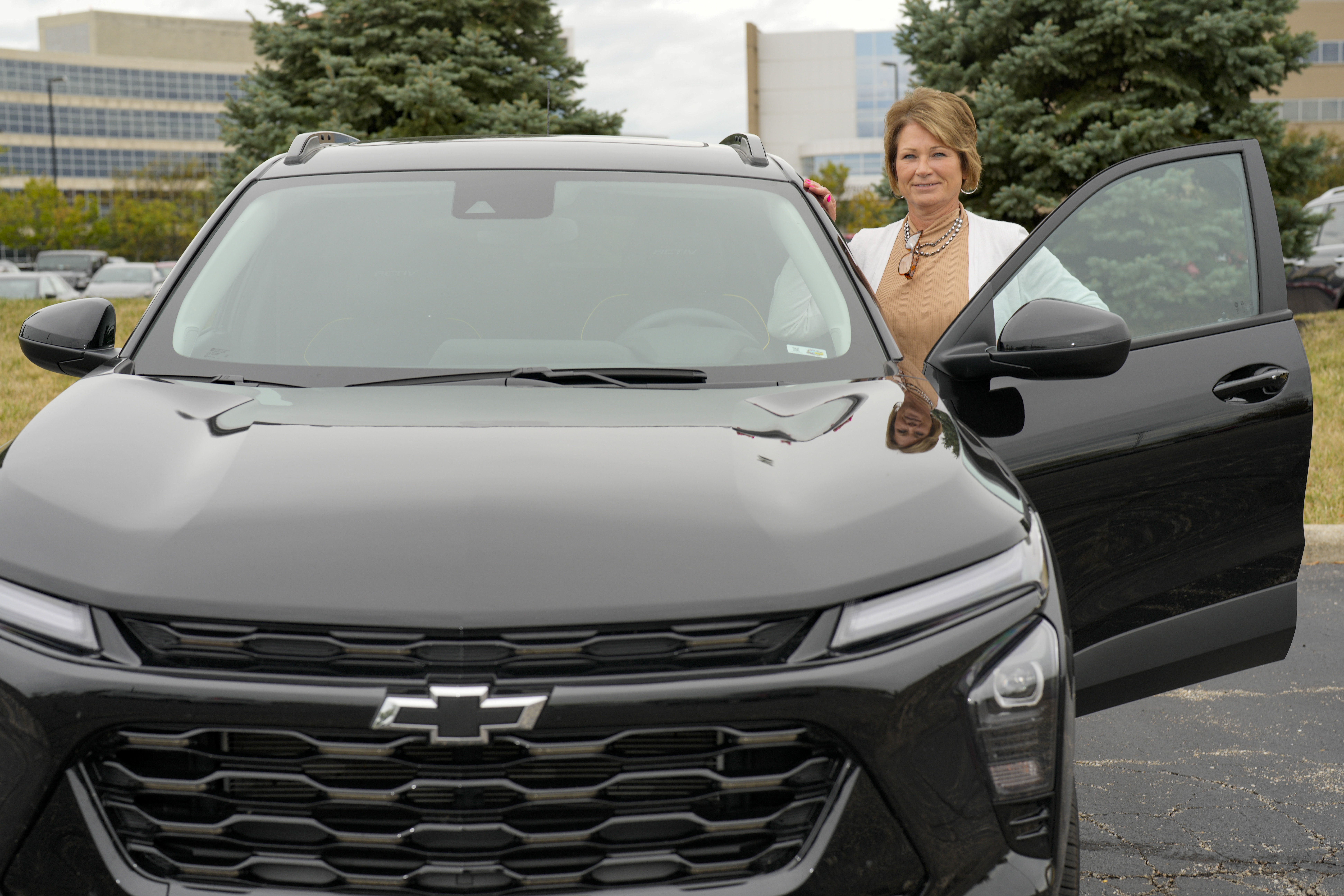 Michelle Chumley poses with her new Chevrolet Trax compact SUV, Thursday, Sept. 26, 2024, in West Chester, Ohio. (AP Photo/Jeff Dean)