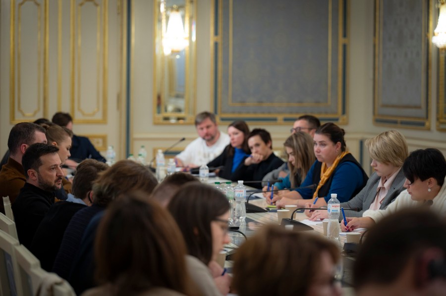 In this photo provided by the Ukrainian Presidential Press Office, Ukrainian President Volodymyr Zelenskyy, left, talks with Ukrainian journalists in Kyiv, Ukraine, Monday, Oct. 21, 2024. (Ukrainian Presidential Press Office via AP)