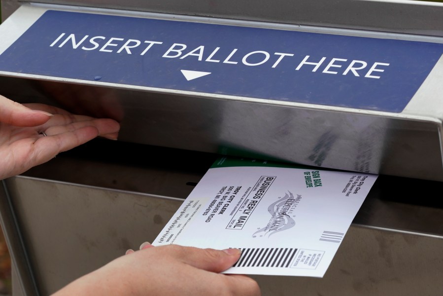 FILE - A Michigan voter inserts her absentee voter ballot into a drop box in Troy, Mich. on Oct. 15, 2020. (AP Photo/Paul Sancya, File)