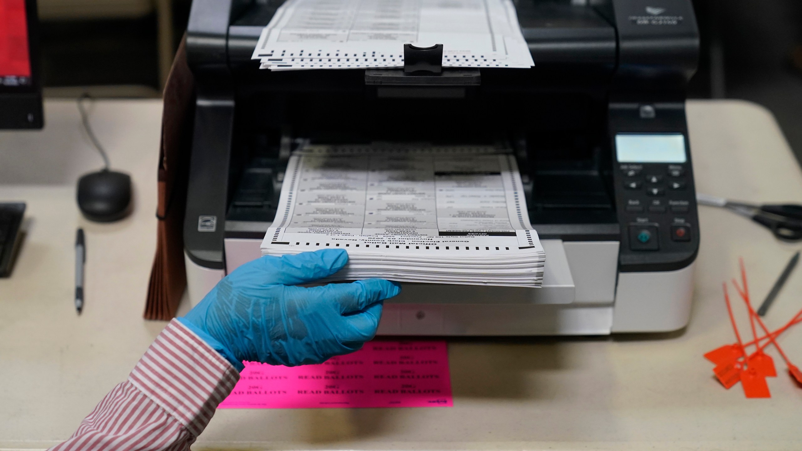 FILE - A county worker loads mail-in ballots into a scanner that records the votes at a tabulating area at the Clark County Election Department, Oct. 29, 2020, in Las Vegas. (AP Photo/John Locher, File)