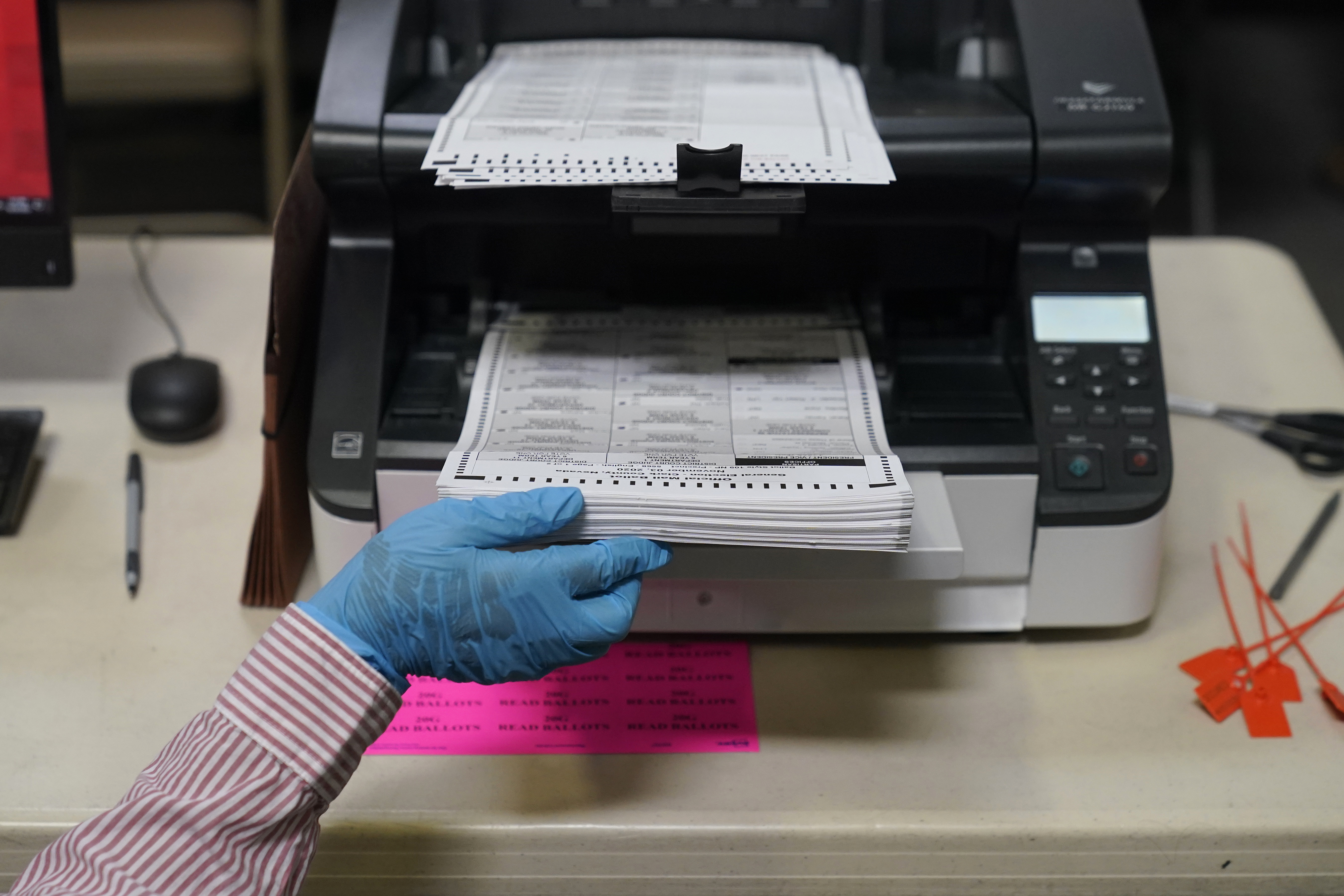 FILE - A county worker loads mail-in ballots into a scanner that records the votes at a tabulating area at the Clark County Election Department, Oct. 29, 2020, in Las Vegas. (AP Photo/John Locher, File)