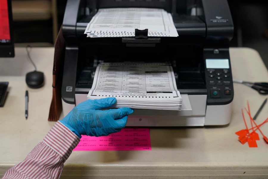 FILE - A county worker loads mail-in ballots into a scanner that records the votes at a tabulating area at the Clark County Election Department, Oct. 29, 2020, in Las Vegas. (AP Photo/John Locher, File)