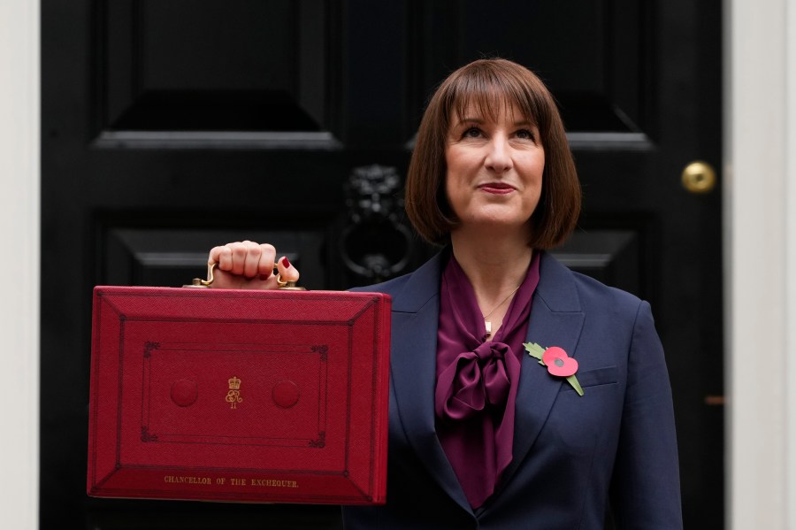 Britain's Chancellor of the Exchequer, Rachel Reeves, looks up as she holds up the traditional red ministerial box containing her budget speech, as she poses for the media outside No 11 Downing Street, before departing to the House of Commons to deliver the budget in London, Wednesday, Oct. 30, 2024. (AP Photo/Kirsty Wigglesworth)