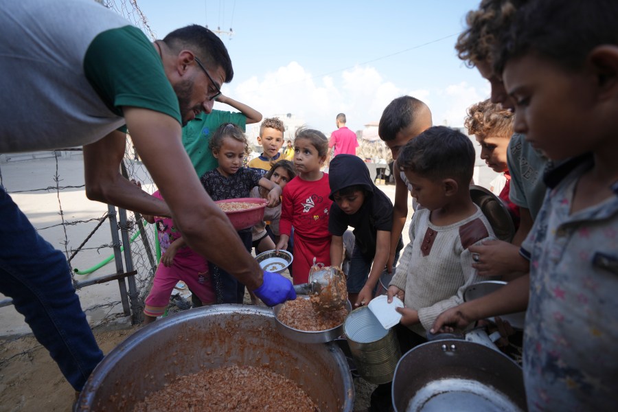 Displaced Palestinian children queue for food in a camp in Deir al-Balah, Gaza Strip, Friday, Oct. 18, 2024. (AP Photo/Abdel Kareem Hana)