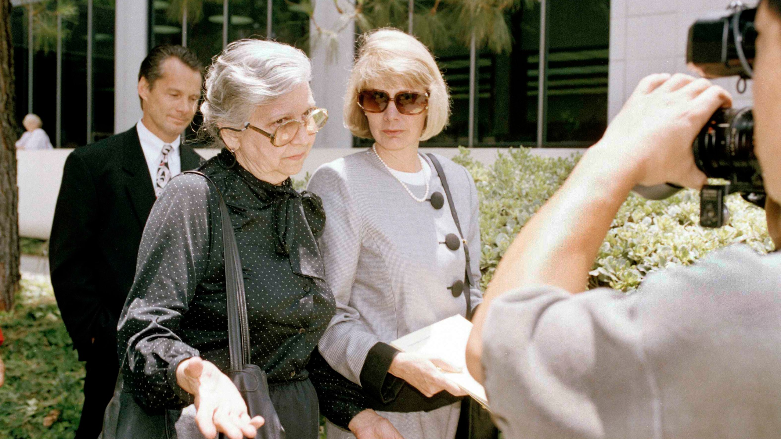 FILE - Maria Menendez, grandmother of two Beverly Hills brothers charged with murdering their millionaire parents, left, encounters news cameras as Jill Lansing, one of the defense attorneys in the case, looks on, outside the Van Nuys courthouse in Los Angeles, June 14, 1993. (AP Photo/Mark J. Terrill., File)