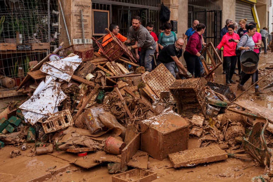 People clean mud from a shop affected by floods in Chiva, Spain, Friday, Nov. 1, 2024. (AP Photo/Manu Fernandez)