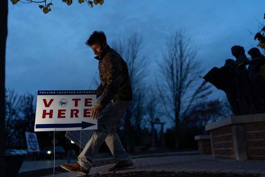 Election official Anthony Salinger removes a sign outside the polling site at Ford Community and Performing Arts Center as early in-person voting comes to an end, Sunday, Nov. 3, 2024, in Dearborn, Mich. (AP Photo/David Goldman)