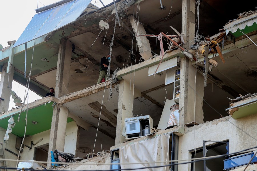 People inspect a destroyed building hit in an Israeli airstrike, in the southern port city of Sidon, Lebanon, Sunday, Nov. 3, 2024. (AP Photo/Mohammed Zaatari)