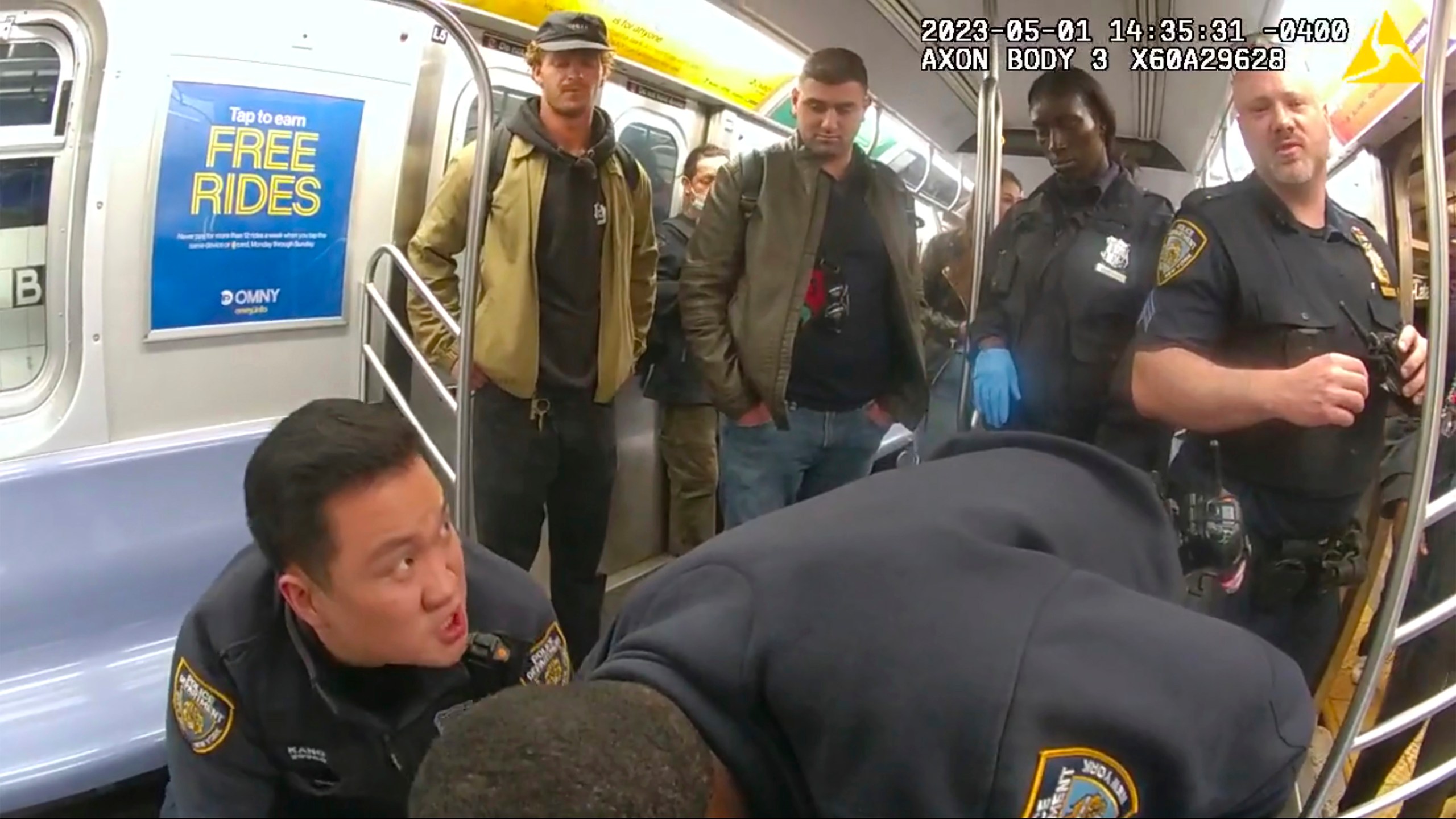 This image from body camera video provided by New York City Police Department, Daniel Penny, standing at left, looks on in a New York City subway car as officers attempt to revive Jordan Neely onMay 5, 2023. (New York City Police Department via AP)