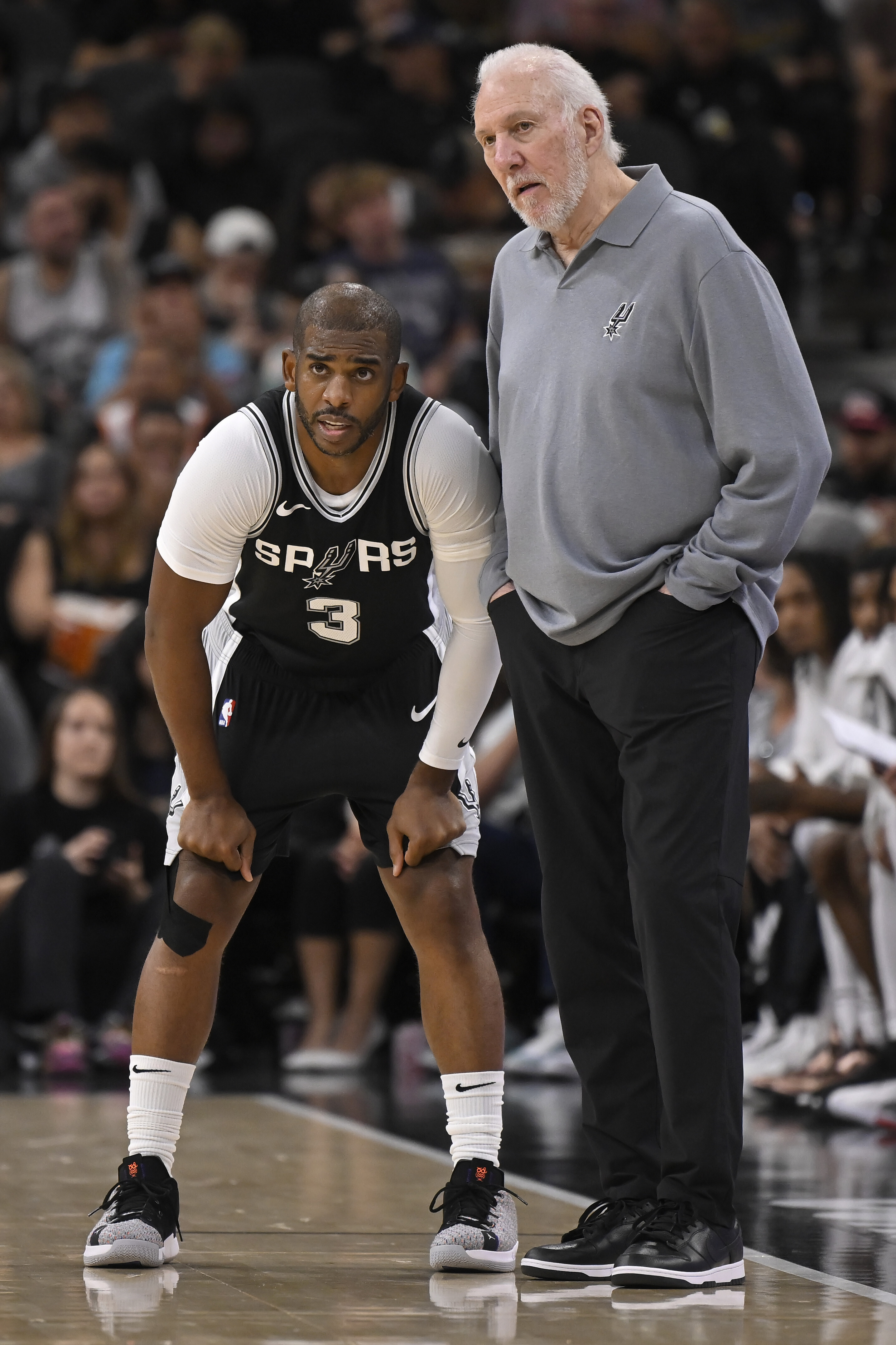 San Antonio Spurs head coach Gregg Popovich, right, speaks with Spurs guard Chris Paul, left, during the first half of an NBA basketball game against the Houston Rockets, Monday, Oct. 28, 2024, in San Antonio. (AP Photo/Darren Abate)