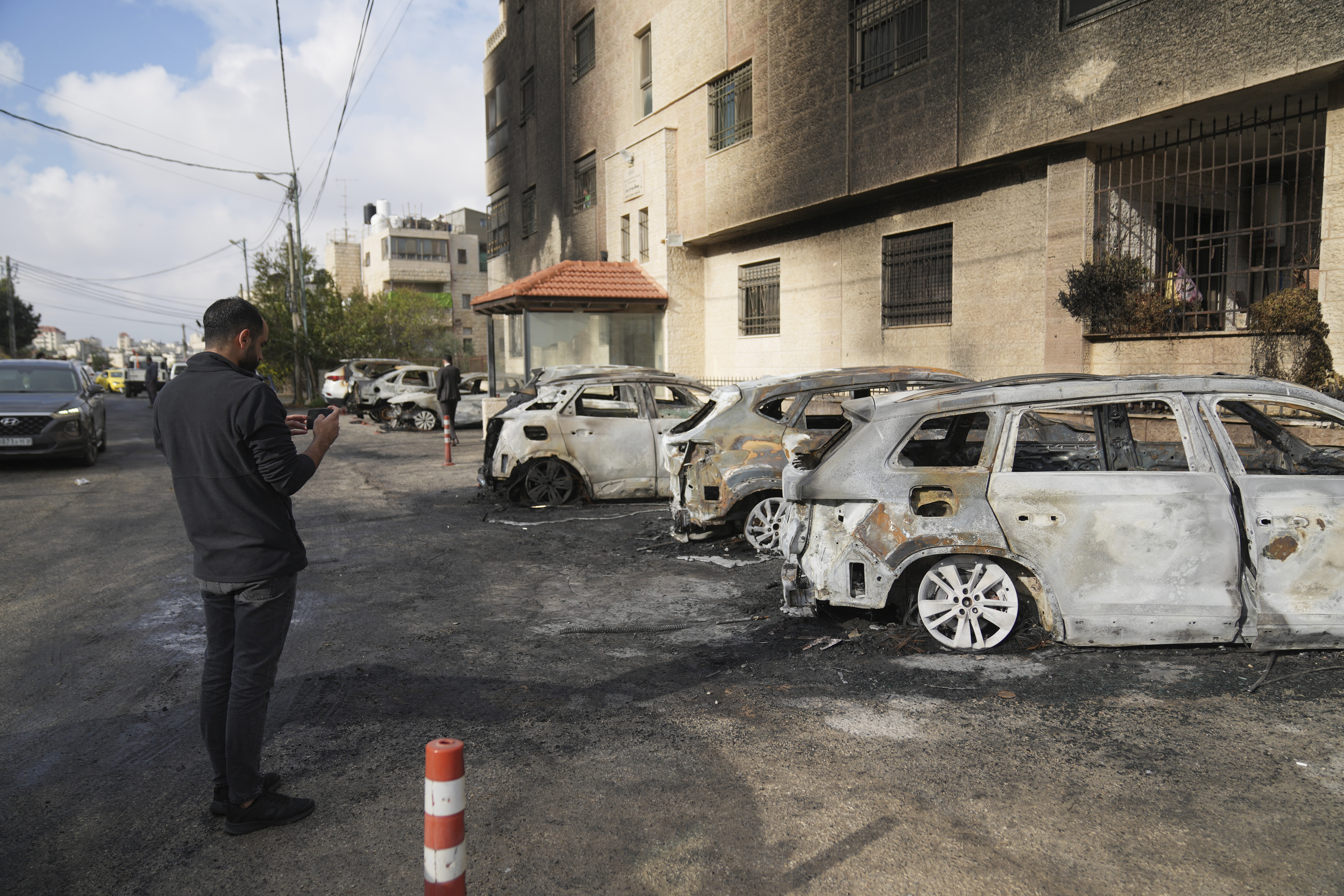 Palestinians inspect vehicles that were burnt during an early morning attack by Israeli settlers, that left at least 18 burnt vehicles, on the outskirts of the West Bank city of al-Bireh Monday, Nov. 4, 2024. (AP Photo/Nasser Nasser)